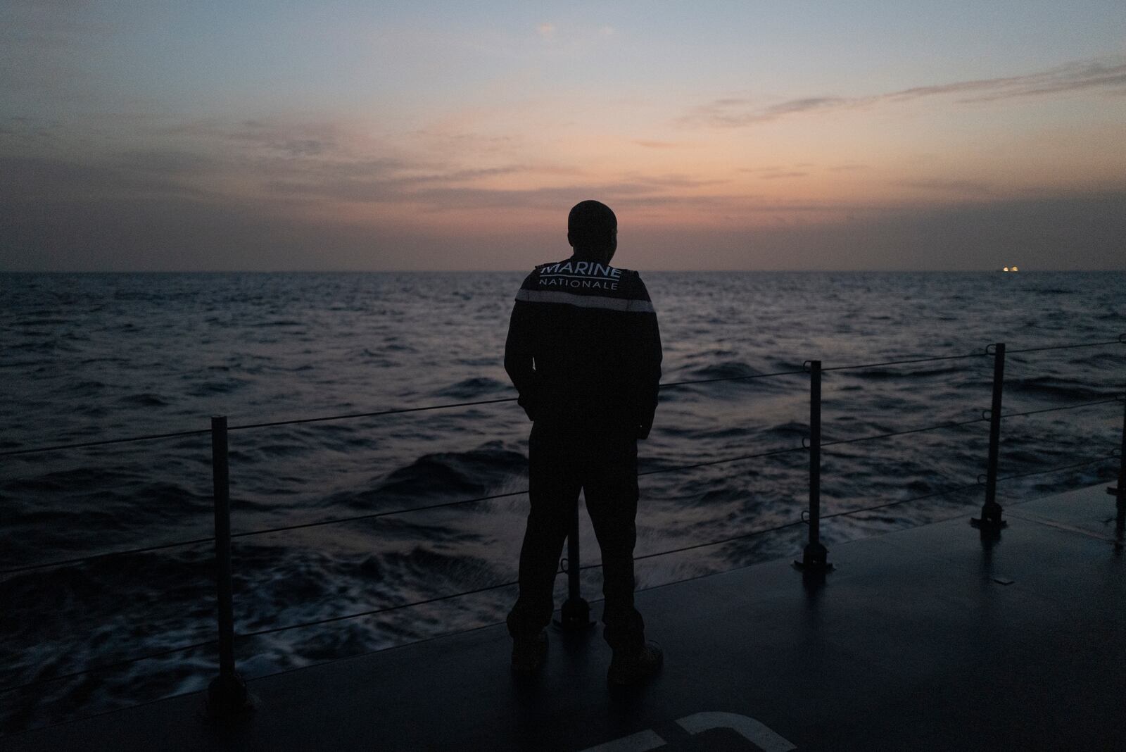 A sailor observes the sunrise from the deck of the offshore patrol vessel Niani during a mission to search for illegal migrant boats near the coast of Dakar, Senegal, Saturday, Nov.16, 2024. (AP Photo/Sylvain Cherkaoui)