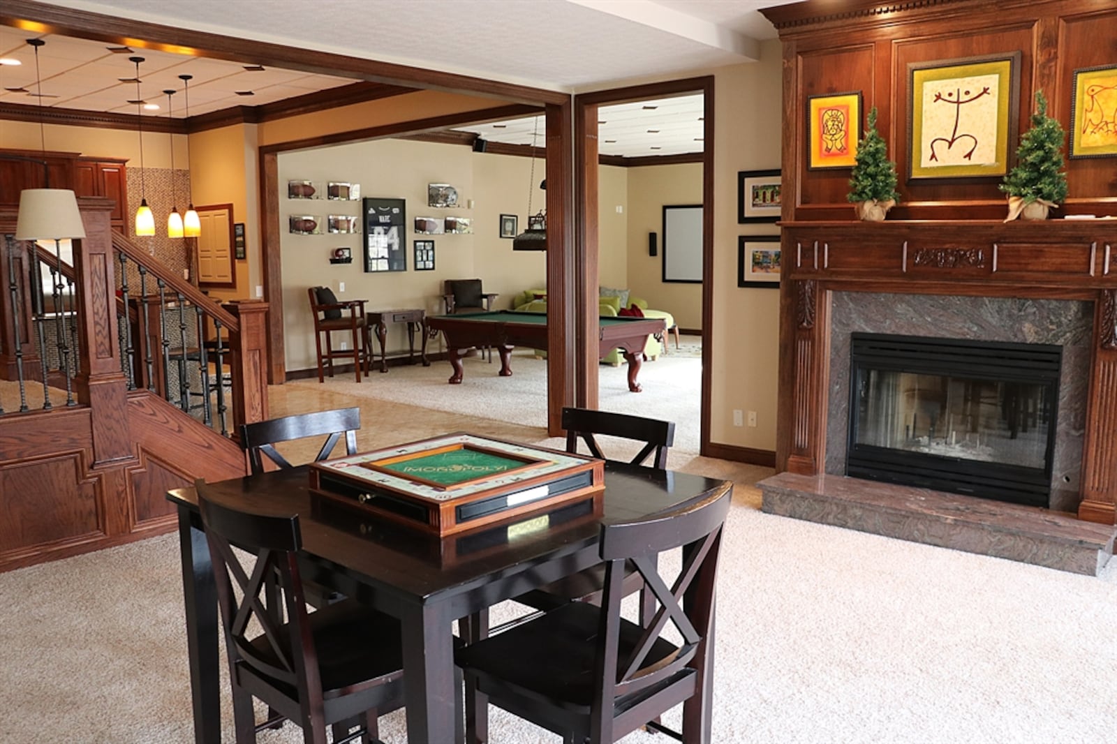 Four-steps down is the family room with a gas fireplace that has an ornate wood mantel and marble surround. Tucked into one corner is a radius wet bar with mosaic tile design and extended counter. Behind the bar is an abundance of cabinetry with sink and large appliance nook. 