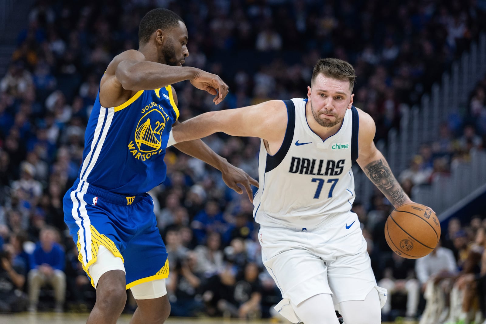 Golden State Warriors forward Andrew Wiggins (22) defends against Dallas Mavericks forward Luka Dončić (77) during the first half of an NBA basketball game Sunday, Dec. 15, 2024, in San Francisco. (AP Photo/Benjamin Fanjoy)