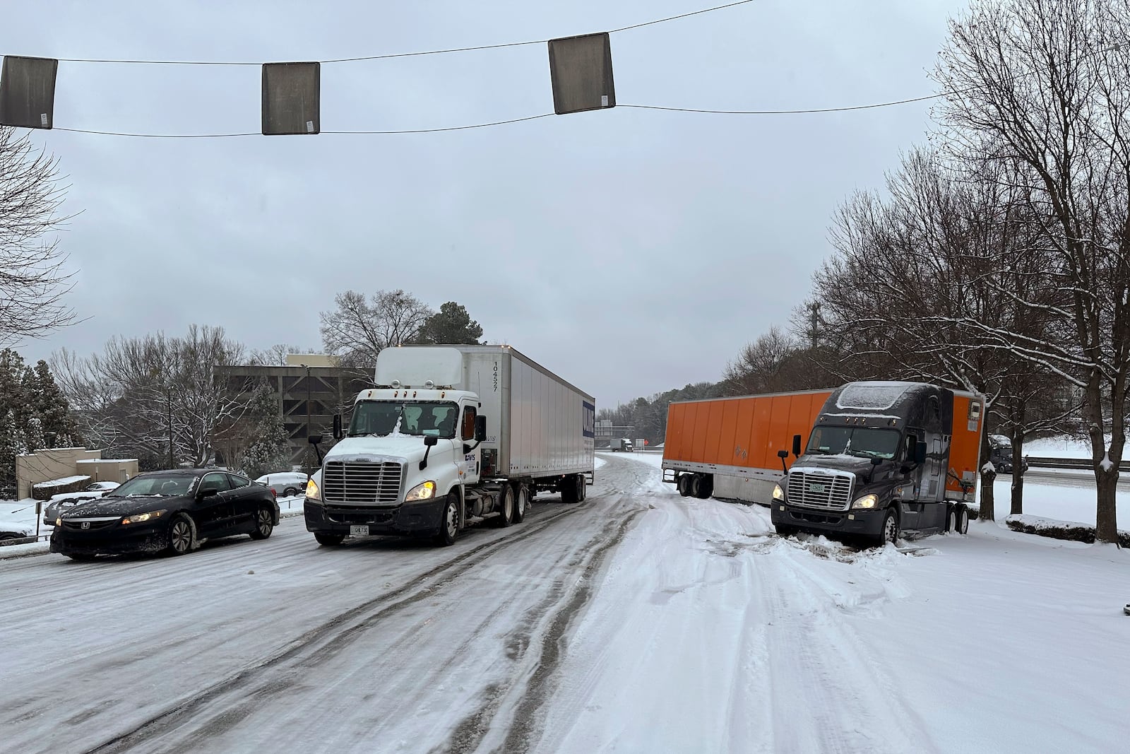 A truck is jackknifed as another spins its wheels on a slushy offramp off Interstate 285 northeast of downtown in Atlanta on Friday, Jan. 10, 2025. (AP Photo/Jeff Amy)