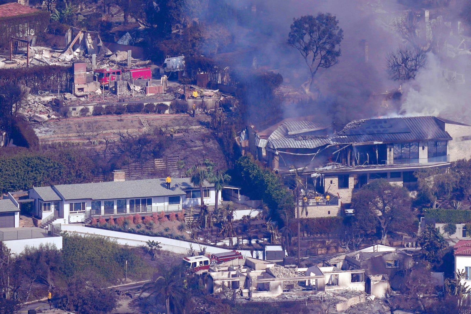 Firefighters protect what is left of homes from the Palisades Fire, Thursday, Jan. 9, 2025, in Malibu, Calif. (AP Photo/Mark J. Terrill)