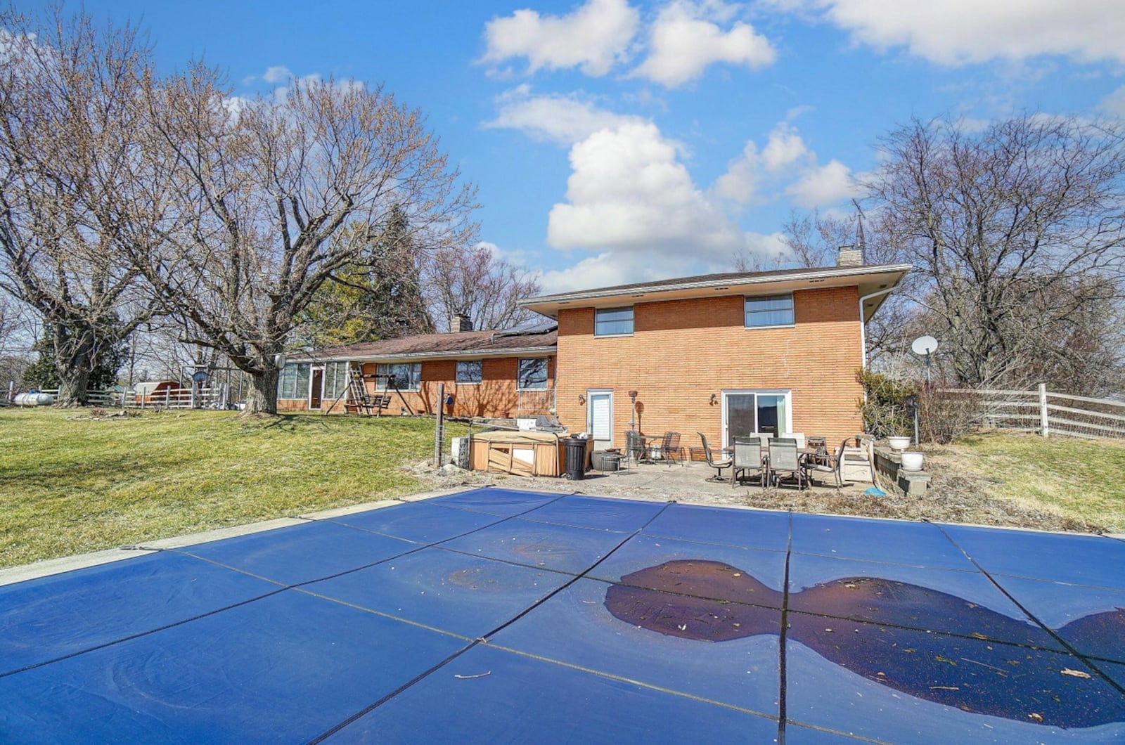 The rear of the home features a concrete patio and in ground pool with diving board.