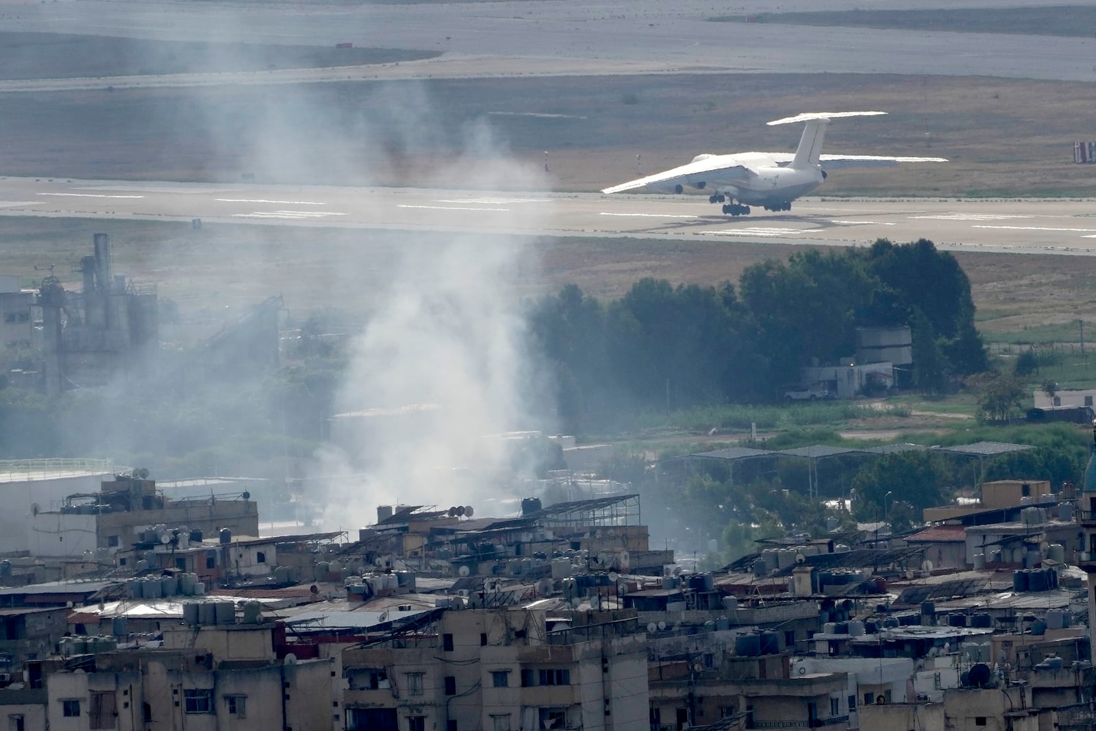 A plane take off from Rafik Hariri international airport as smoke of a past Israeli airstrike still rise from Dahiyeh, in Beirut, Lebanon, Monday, Oct. 14, 2024. (AP Photo/Hussein Malla)