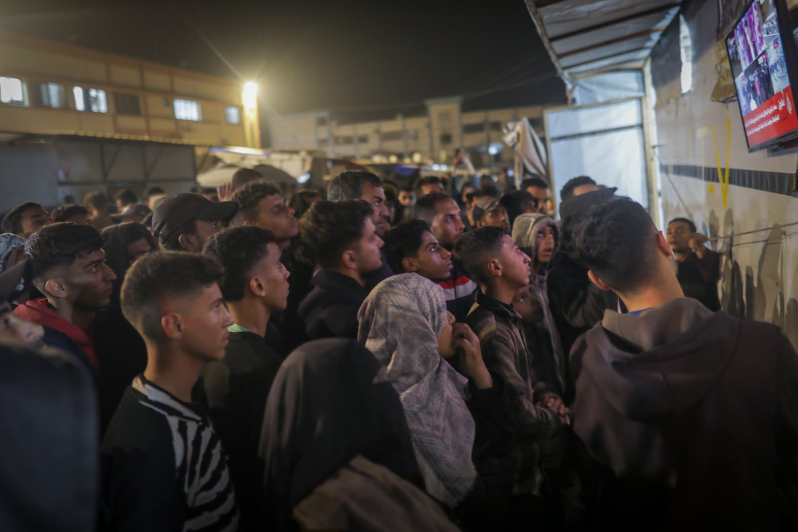 Palestinians watch TV as they await the imminent announcement of a ceasefire deal between Hamas and Israel in Khan Younis, central Gaza Strip, Wednesday, Jan. 15, 2025.(AP Photo/(AP Photo/Jehad Alshrafi)