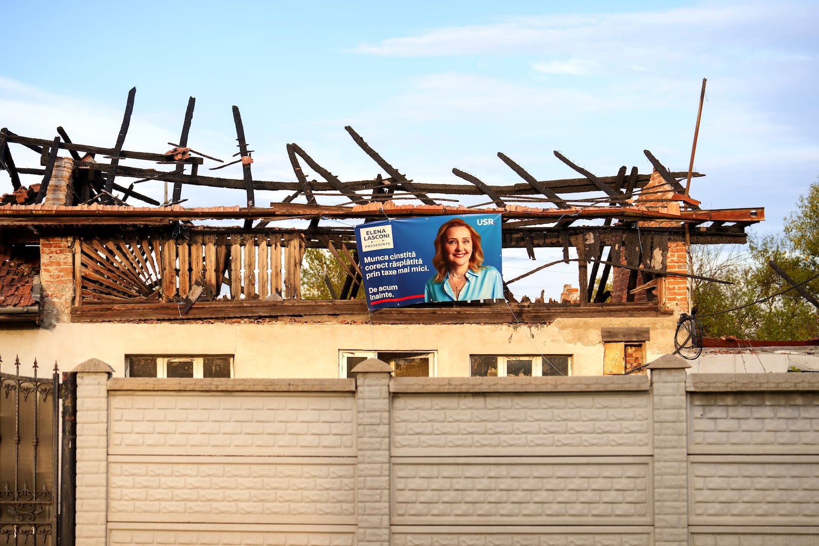 An electoral poster of presidential candidate Elena Lasconi is placed on a fire damaged building in Farcasesti Mosneni, southern Romania, Friday, Oct. 11, 2024. (AP Photo/Vadim Ghirda)