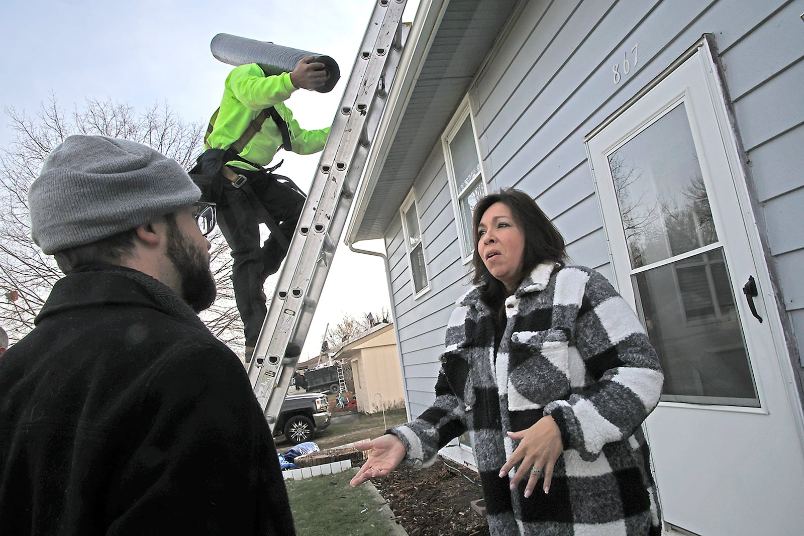 Burnadette Underwood talks with John Badden, marketing manager for Van Martin Roofing, about her need for a new roof on her Park Layne house Thursday, Dec. 21, 2023. Burnadette is the winner of Van Martin Roofing's "Win a New Roof on the House" program, which gives a new roof to a lucky home owner in the Miami Valley twice a year. Burnadette, who is currently taking care of her elderly father, who has cancer, was nominated by her daughter and was selected from over 50 applicants. BILL LACKEY/STAFF