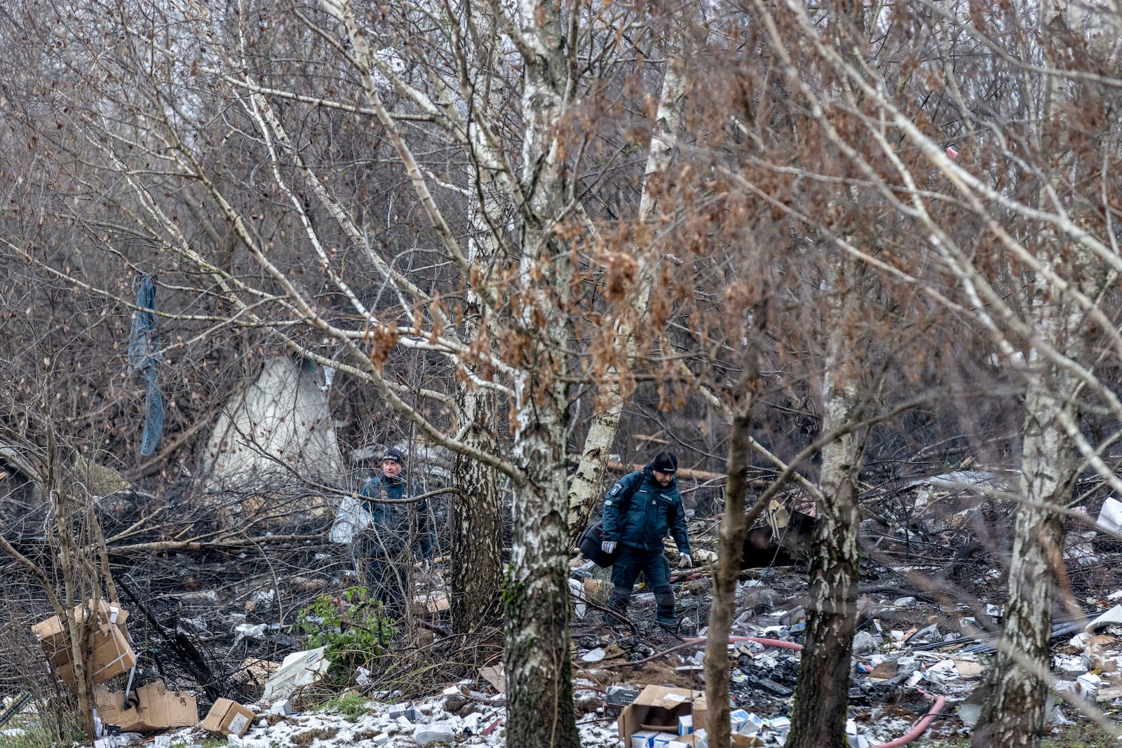 Lithuanian police investigators work near the site where a DHL cargo plane crashed into a house near the Lithuanian capital Vilnius, Lithuania, Lithuania, Monday, Nov. 25, 2024. (AP Photo/Mindaugas Kulbis)