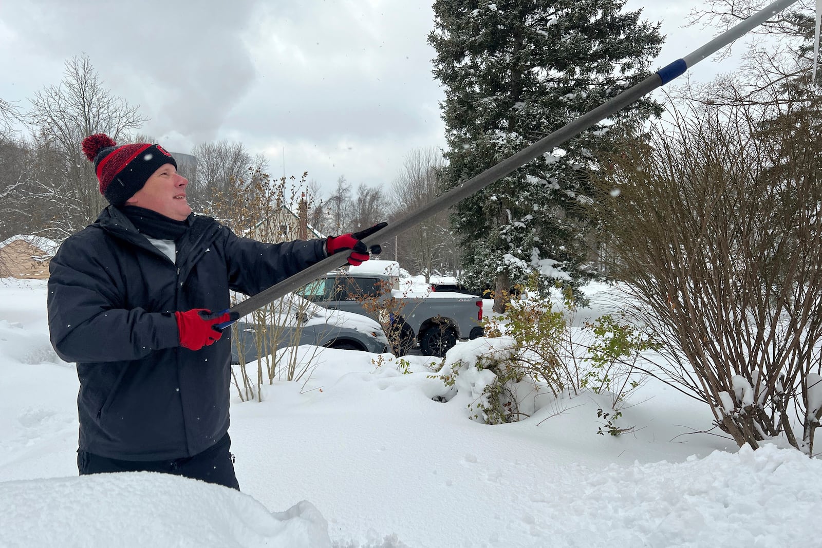 Resident Todd Brainard cleans snow off of the roof of his home in North Perry, Ohio on Tuesday, Dec. 3, 2024. (AP Photo/Patrick Aftoora-Orsagos)