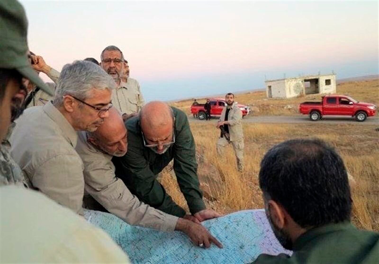 FILE - This file photo provided on Oct. 20, 2017 by the government-controlled Syrian Central Military Media, shows Iran's army chief of staff Maj. Gen. Mohammad Bagheri, left, looking at a map with senior officers from the Iranian military as they visit a front line in the northern province of Aleppo, Syria. (Syrian Central Military Media, via AP, File)