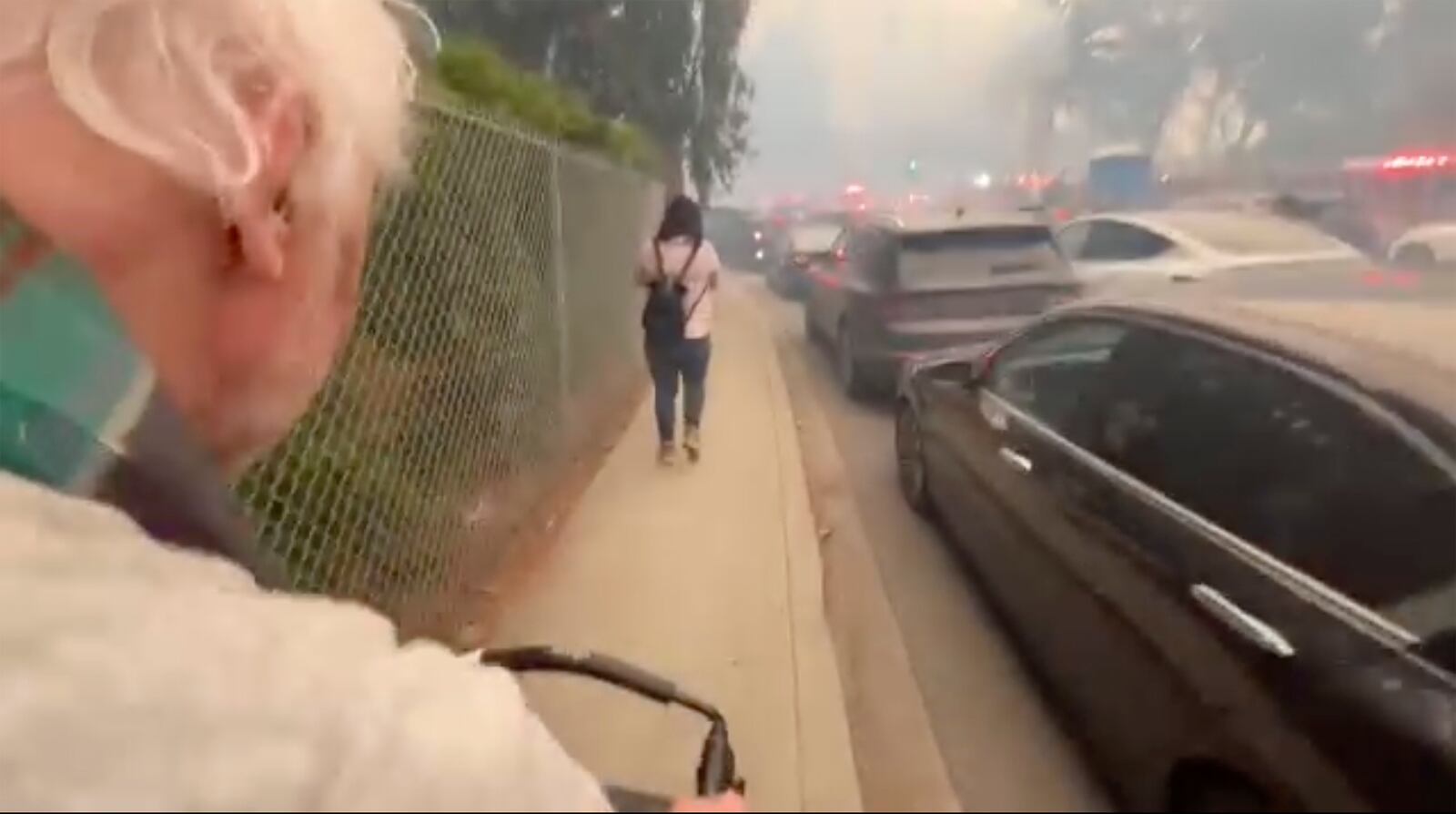 This image taken from video provided by Aaron Samson shows his 83-year-old father-in-law escaping the wildfires after they evacuated a vehicle near Glenhaven, Calif., on Tuesday, Jan. 7, 2025. (Aaron Samson via AP(