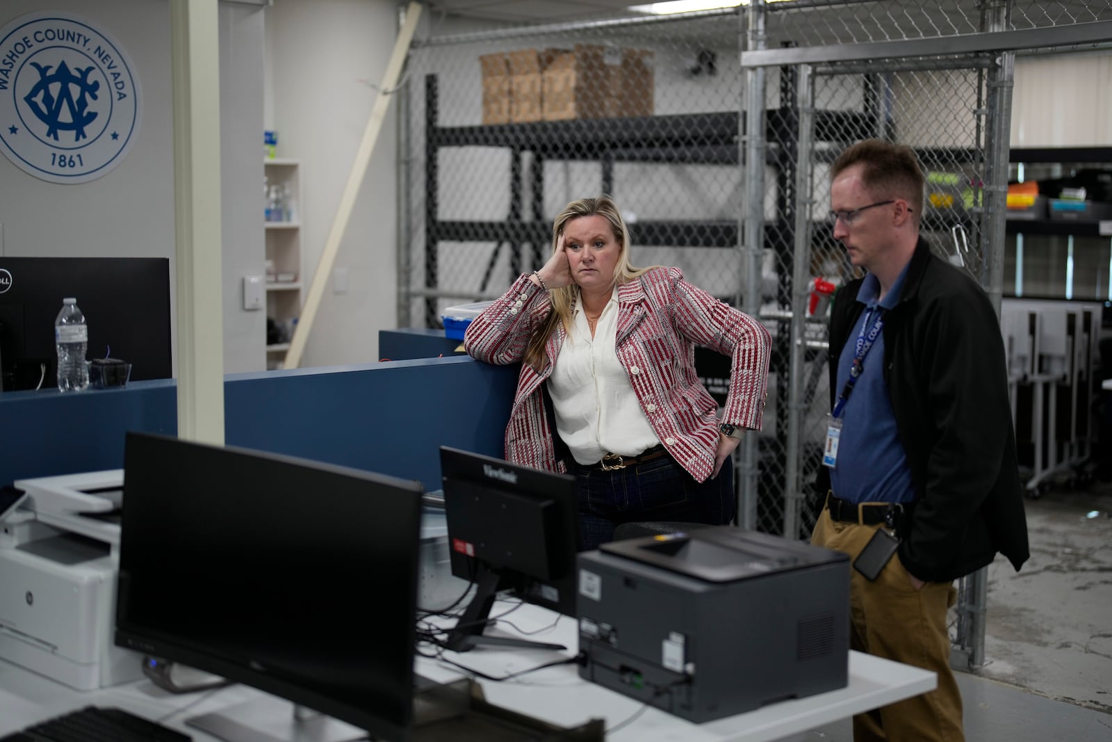 Cari-Ann Burgess, left, interim Registrar of Voters for Washoe County, Nev., stands with Michael Mulreany, business technologist, while helping prepare the office for elections, Friday, Sept. 20, 2024, in Reno, Nev. (AP Photo/John Locher)