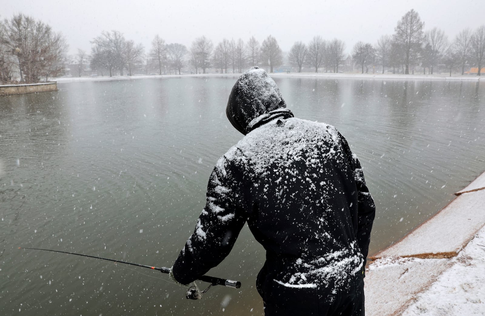 FILE - Ray King fishes for trout during a steady snowfall at the lake in O'Fallon Park in St. Louis, Mo., Feb. 12, 2025. (Robert Cohen/St. Louis Post-Dispatch via AP, File)