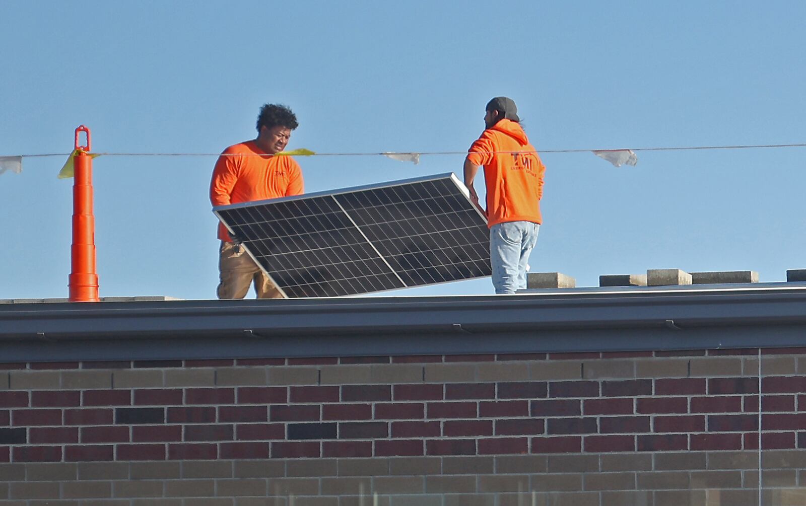 Workers install solar panels on the roof of the new Greenon School Friday. BILL LACKEY/STAFF