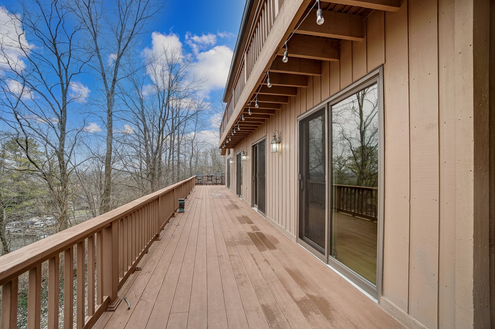 The rear of the home overlooks a wooded lot with two wood wraparound decks and a lower covered concrete patio.