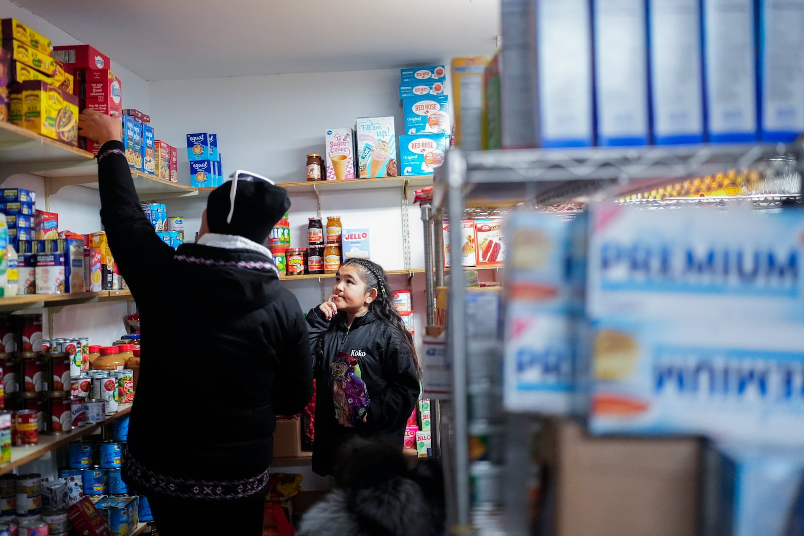 Chloe Gordon, 9, looks at her mother, Amanda Toorak, left, as they shop for packaged goods at Sims Store, one of two small stores in the village in Kaktovik, Alaska, Tuesday, Oct. 15, 2024. (AP Photo/Lindsey Wasson)