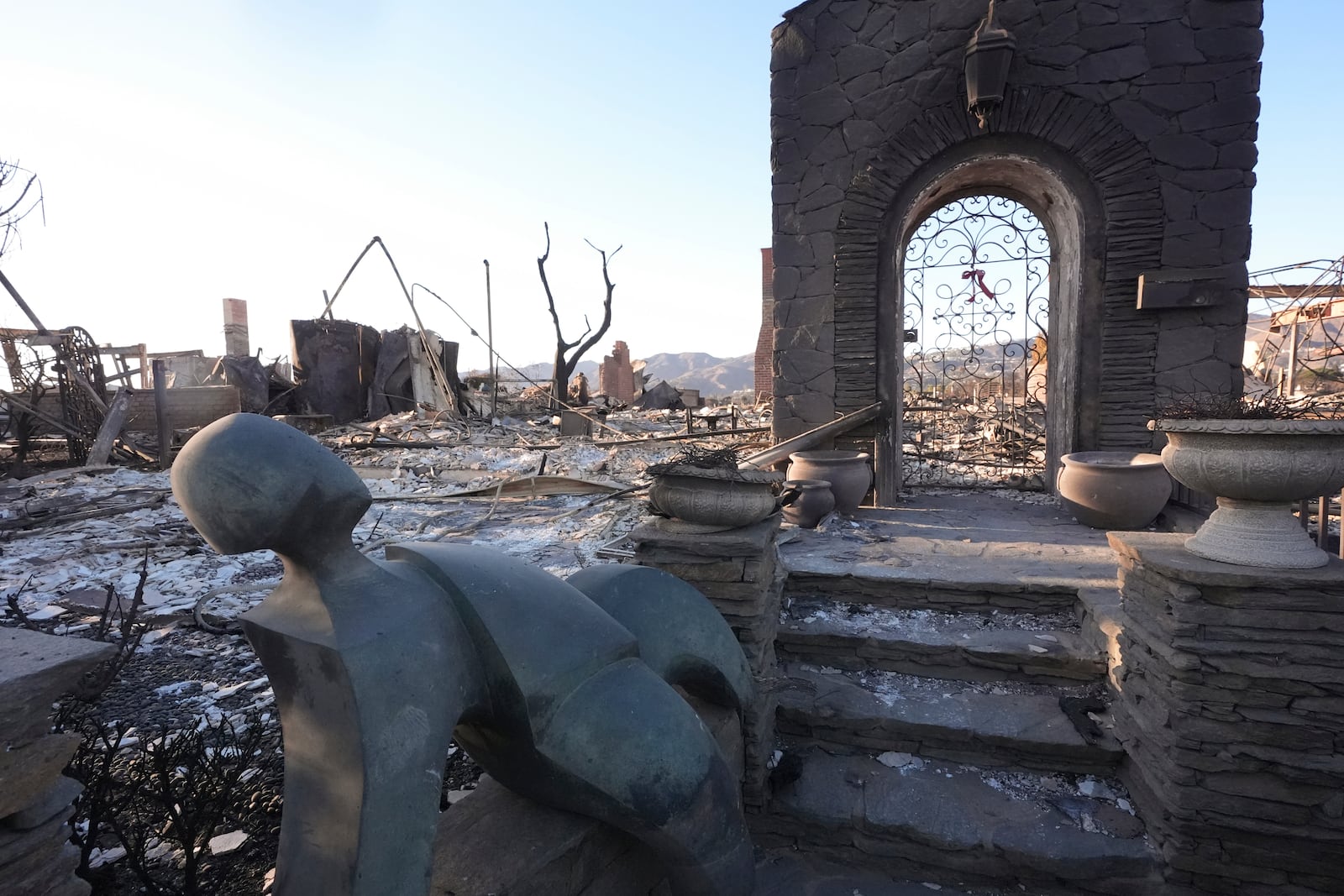 A statue sits outside a home destroyed by the Palisades Fire in the Pacific Palisades neighborhood of Los Angeles, Sunday, Jan. 12, 2025. (AP Photo/Mark J. Terrill)