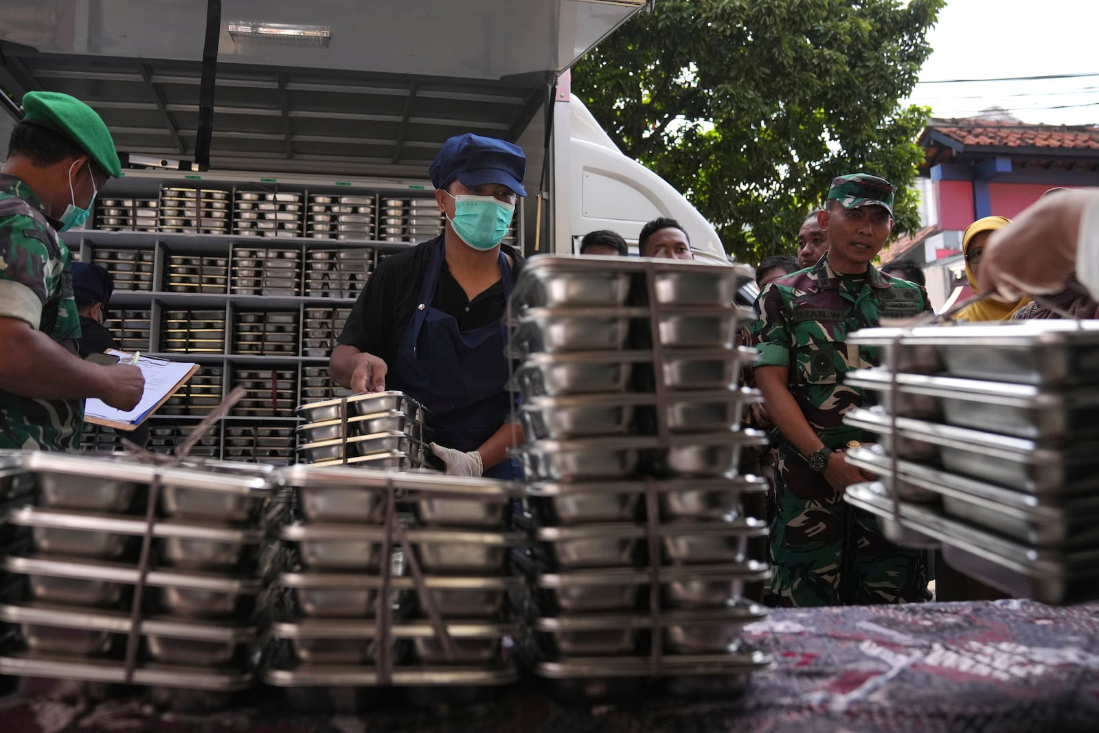 Workers unload food containers to be distributed to classrooms during the kick off of President Prabowo Subianto's ambitious free meal program to feed children and pregnant women nationwide despite critics saying that its required logistics could hurt Indonesia's state finances and economy, at an elementary school in Depok, West Java, Indonesia, Monday, Jan. 6, 2025. (AP Photo/Dita Alangkara)