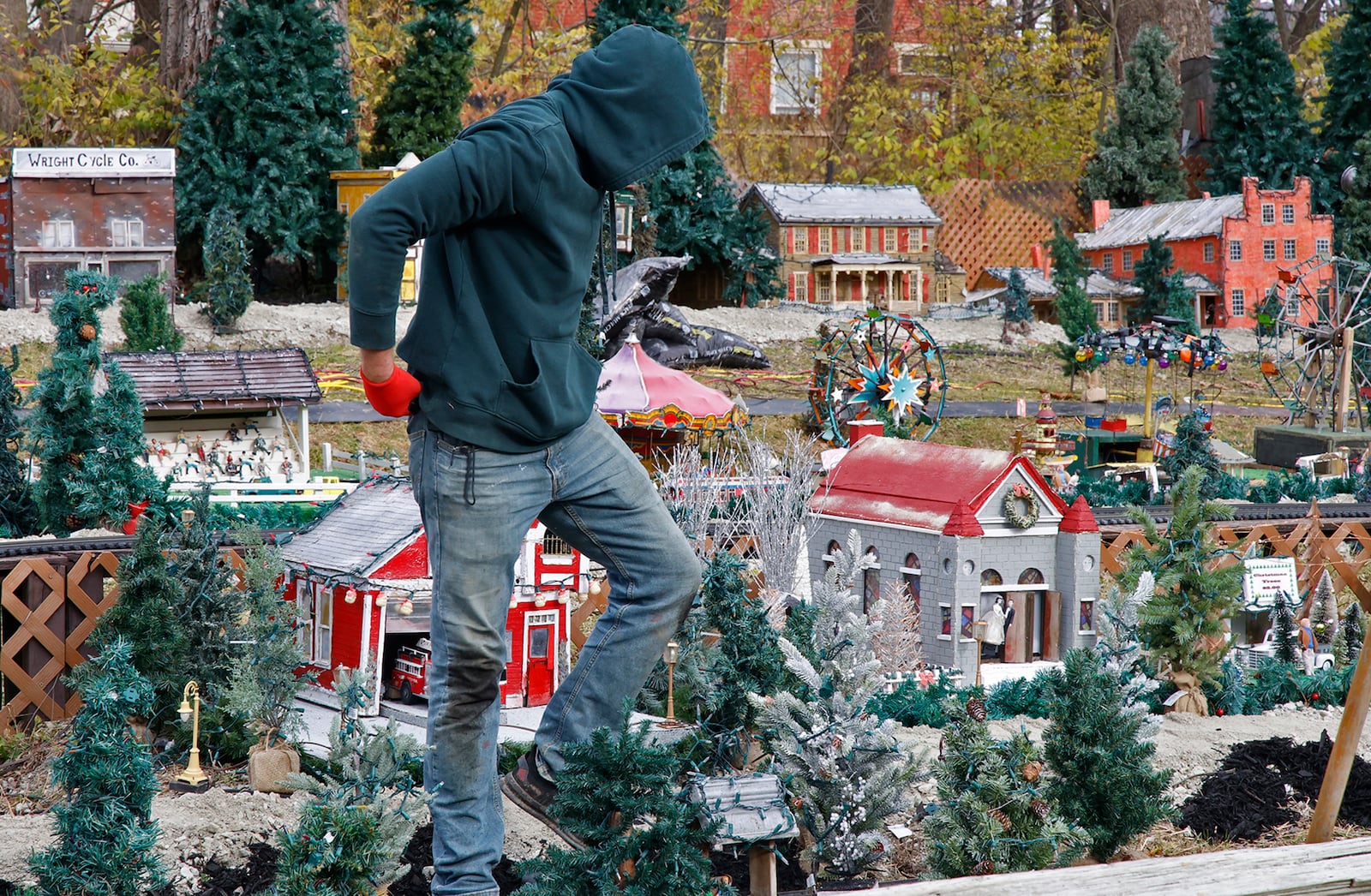 Like a scene from a Godzilla movie, Jack Moore looks like a giant as he gingerly walks through the miniature village at Clifton Mill Monday, Nov. 20, 2023. The staff at Clifton Mill has been busy putting the final touches on their Christmas light display, which starts Friday, Nov. 24th and runs through the holidays. This year, they've added even more lights bringing the total to over five million lights. BILL LACKEY/STAFF