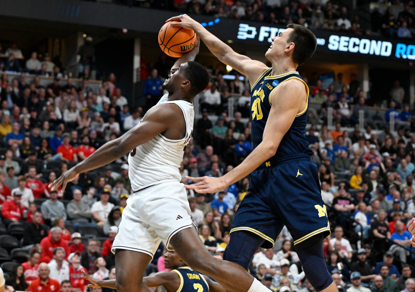 Michigan center Vladislav Goldin, right, blocks a shot by Texas A&M forward Henry Coleman III, left, during the first half in the second round of the NCAA college basketball tournament Saturday, March 22, 2025, in Denver. (AP Photo/John Leyba)