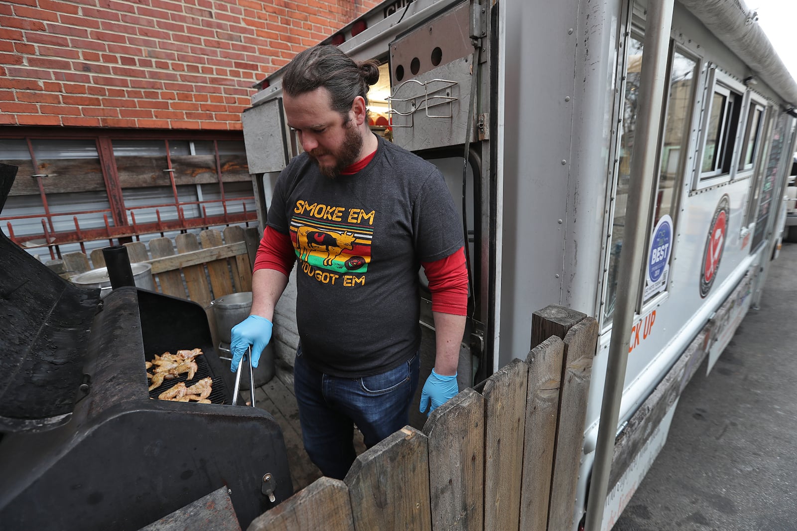 Elliott Martin cooks chicken wings on the grill attached to the Christian Brothers Meat Company food truck parked outside Mother Stewarts Brewery in downtown Springfield Thursday. BILL LACKEY/STAFF