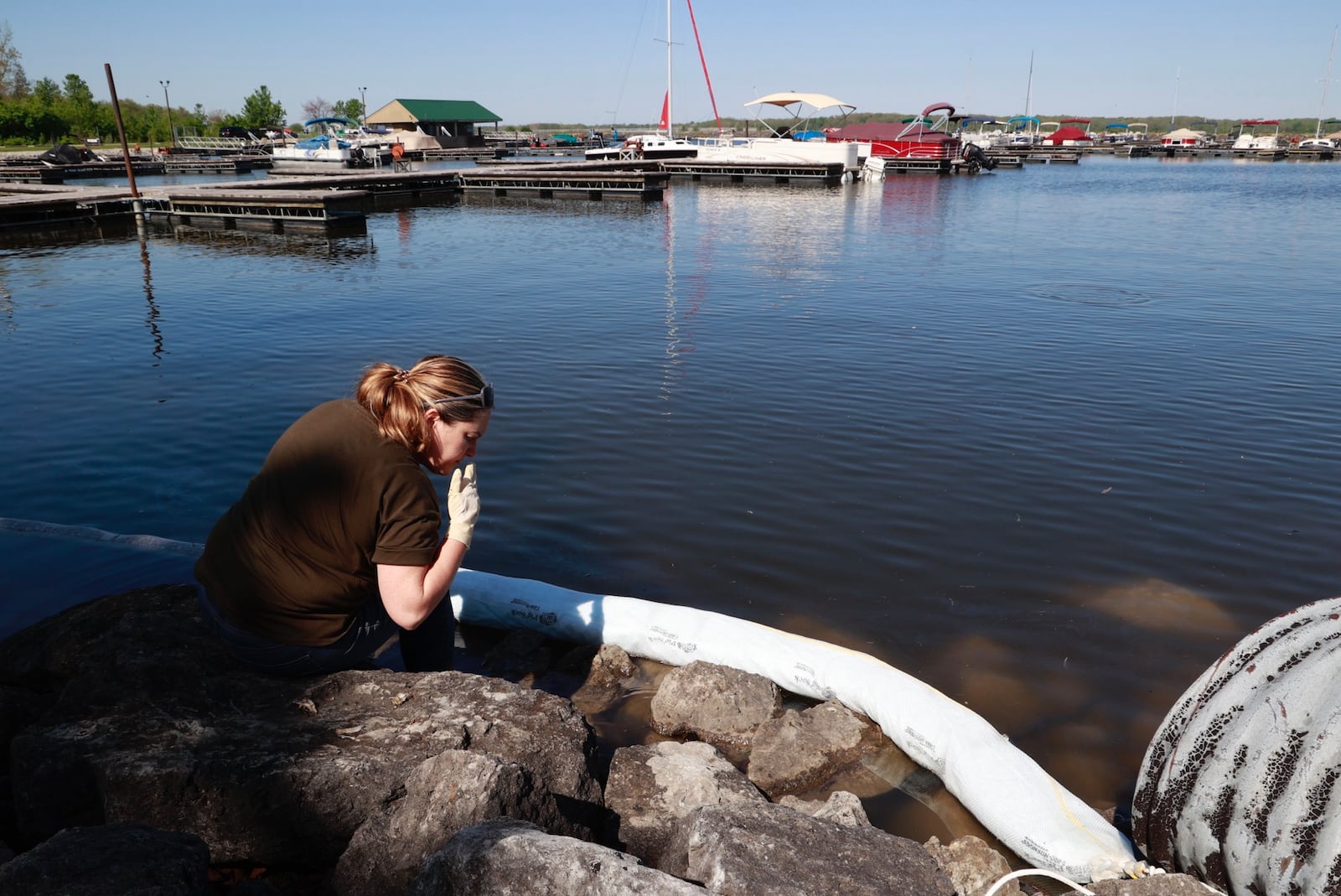 Natalie Foos, from the Ohio Department of Natural Resources, checks out a mysterious film that was detected on the surface of the water in the Buck Creek State Park Marina Tuesday morning. Foos determined that the film was natural and caused by dead plants and fish breaking down in the water. BILL LACKEY/STAFF