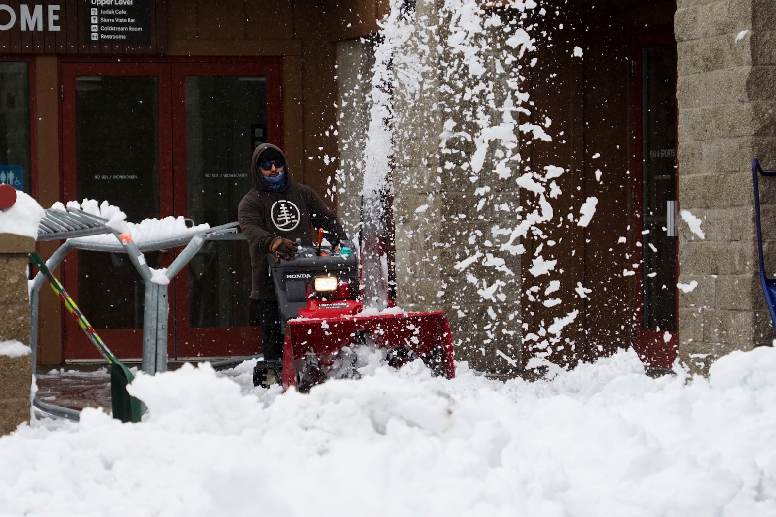 A worker clears the entrance to a building with a snow blower during a storm, Thursday, Nov. 21, 2024, at Sugar Bowl Ski Resort in Norden, Calif. (AP Photo/Brooke Hess-Homeier)