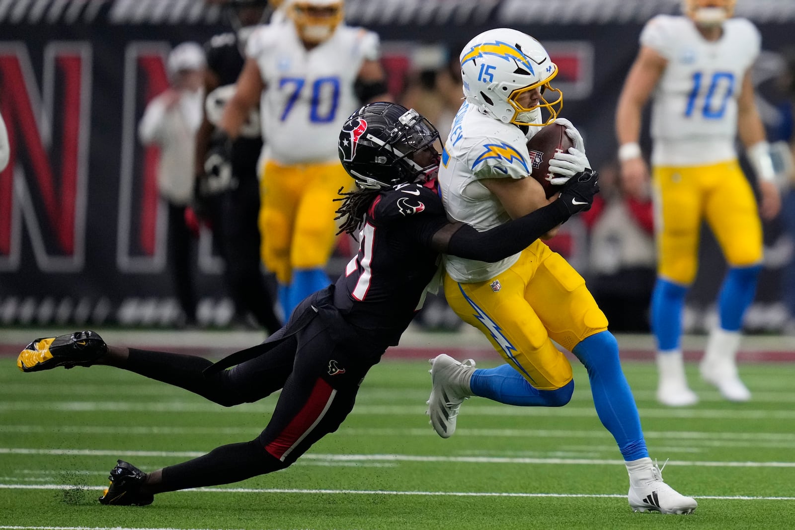 Los Angeles Chargers wide receiver Ladd McConkey (15) is tackled by Houston Texans safety Calen Bullock (21) after catching a pass during the first half of an NFL wild-card playoff football game Saturday, Jan. 11, 2025, in Houston. (AP Photo/Ashely Landis)