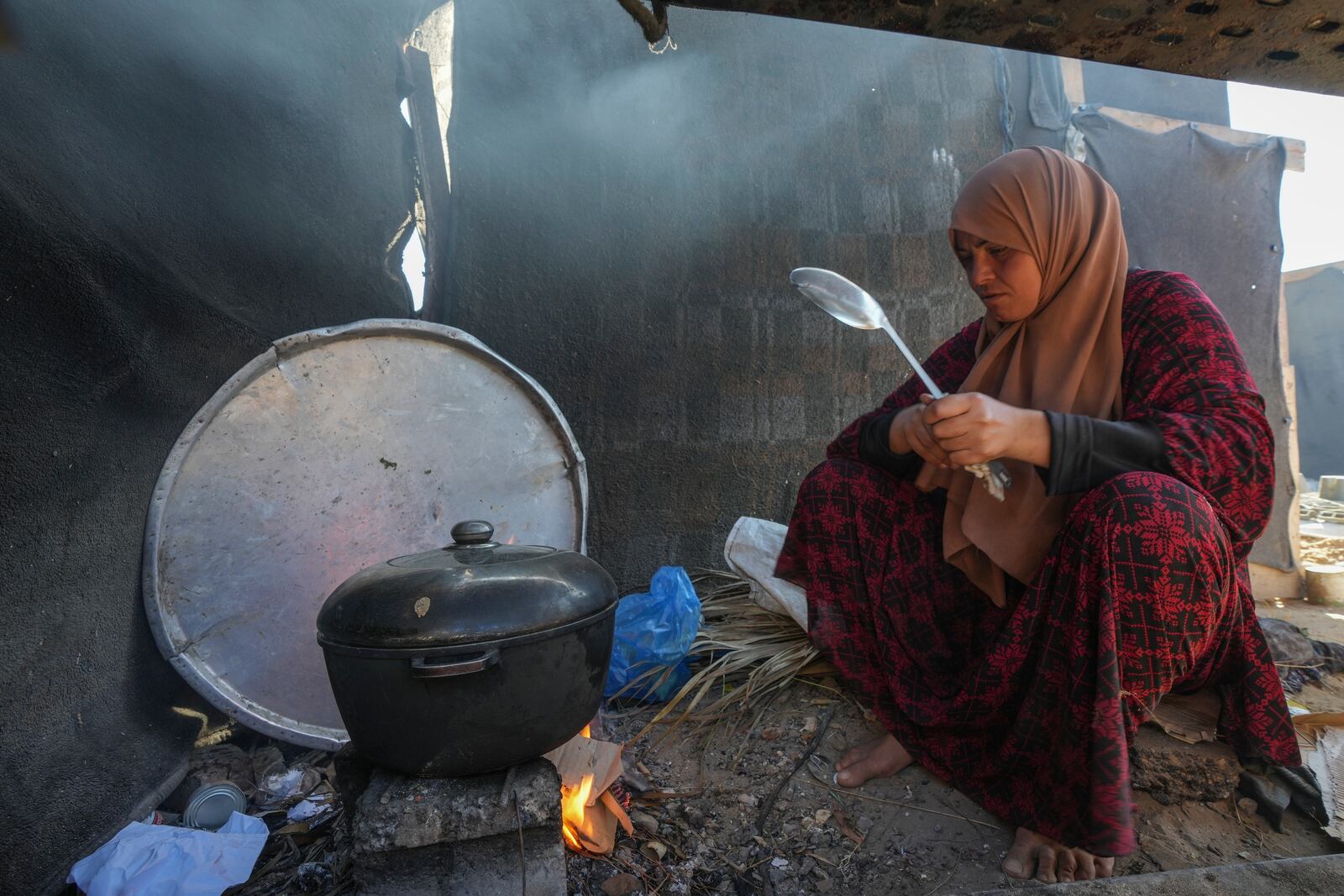 Yasmin Eid cooks at her family's tent in a refugee camp in Deir al-Balah, Gaza Strip, Tuesday, Nov. 19, 2024. (AP Photo/Abdel Kareem Hana)