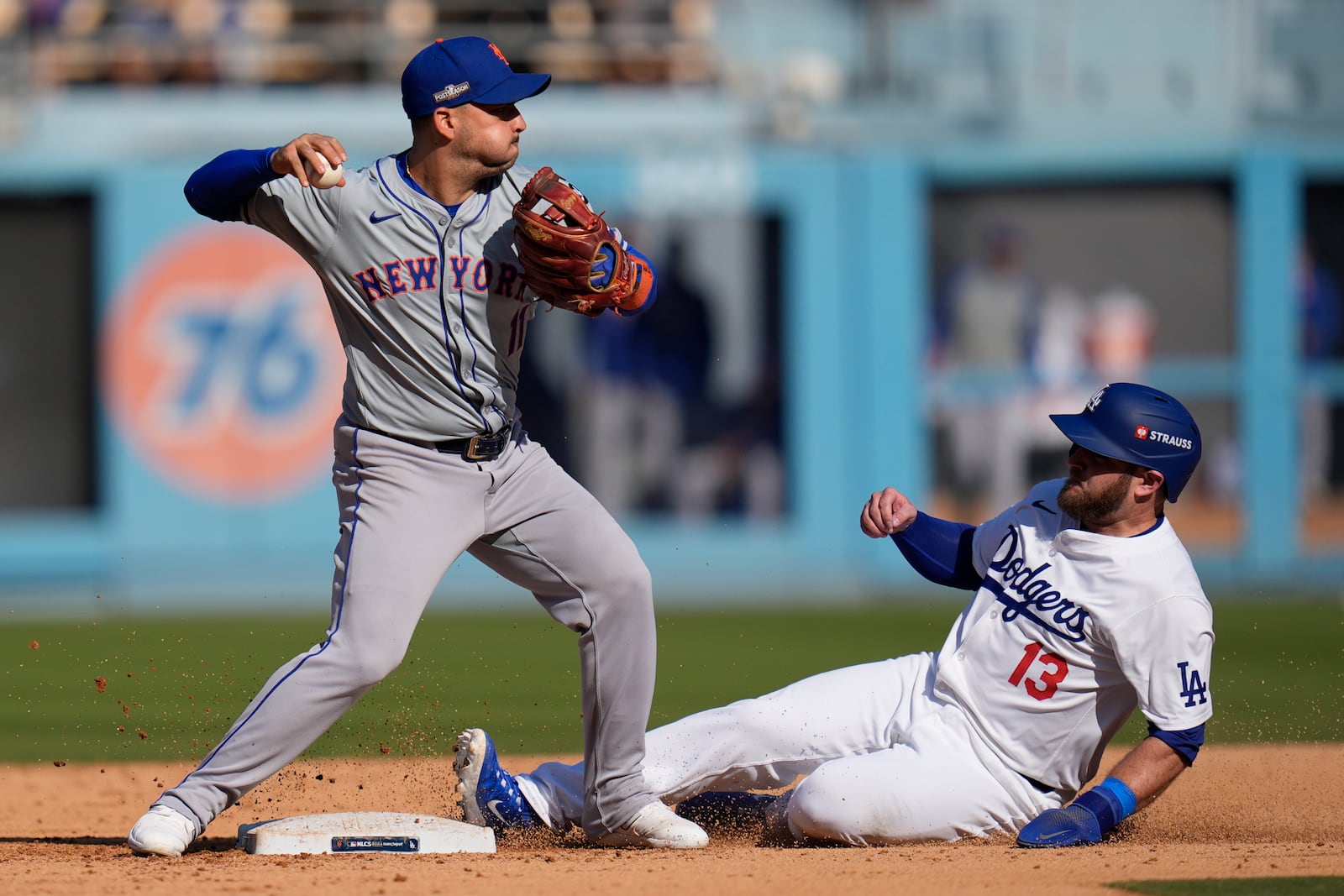 New York Mets second baseman Jose Iglesias, left, throws over Los Angeles Dodgers' Max Muncy to complete a double play on a ground ball from Kiké Hernández during the sixth inning in Game 2 of a baseball NL Championship Series, Monday, Oct. 14, 2024, in Los Angeles. (AP Photo/Gregory Bull)