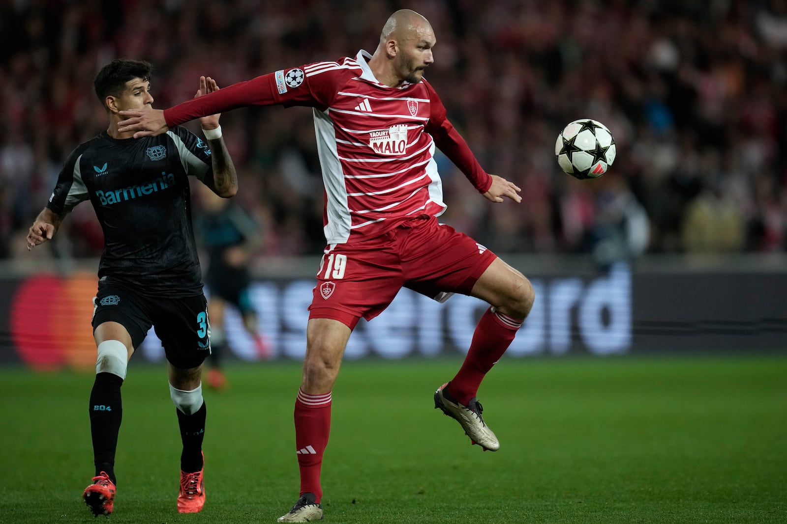 Brest's Ludovic Ajorque receives the ball in front pf Leverkusen's Piero Hincapie during the Champions League opening phase soccer match between Brest and Bayer Leverkusen in Guingamp, western France, Wednesday, Oct. 23, 2024. (AP Photo/Christophe Ena)