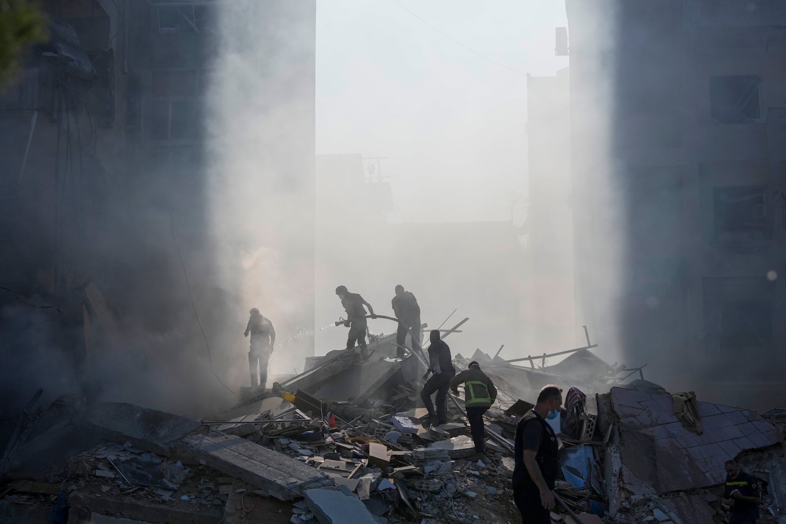 Civil defense workers extinguish a fire as smoke rises from the site of an Israeli airstrike in Tayouneh, Beirut, Lebanon, Friday, Nov. 15, 2024. (AP Photo/Hassan Ammar)