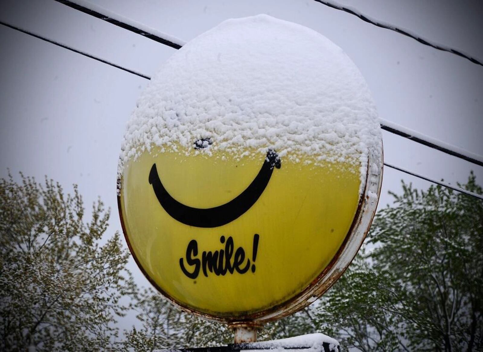 A sign near Enon urges people to smile even though half of the smiley face sign is covered with snow Wednesday after a record April snow fall swept through the area. Marshall Gorby/STAFF