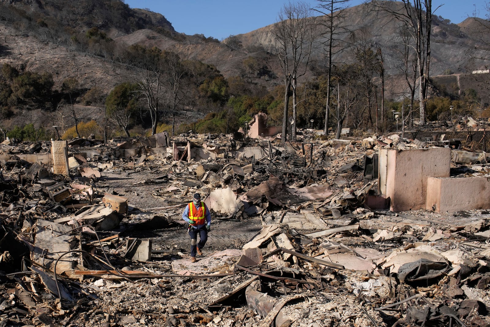 FILE - A worker surveys the damage from the Palisades Fire in the Pacific Palisades neighborhood of Los Angeles, Monday, Jan. 13, 2025. (AP Photo/John Locher, File)