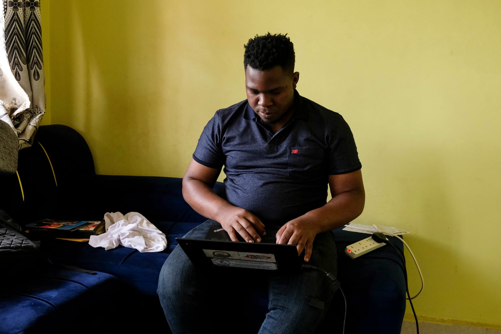 Ugandan human rights activist Kennedy Pius reads a letter from USAID on his laptop at home in Kampala, Uganda, Jan. 28, 2025. (AP Photo/Hajarah Nalwadda)