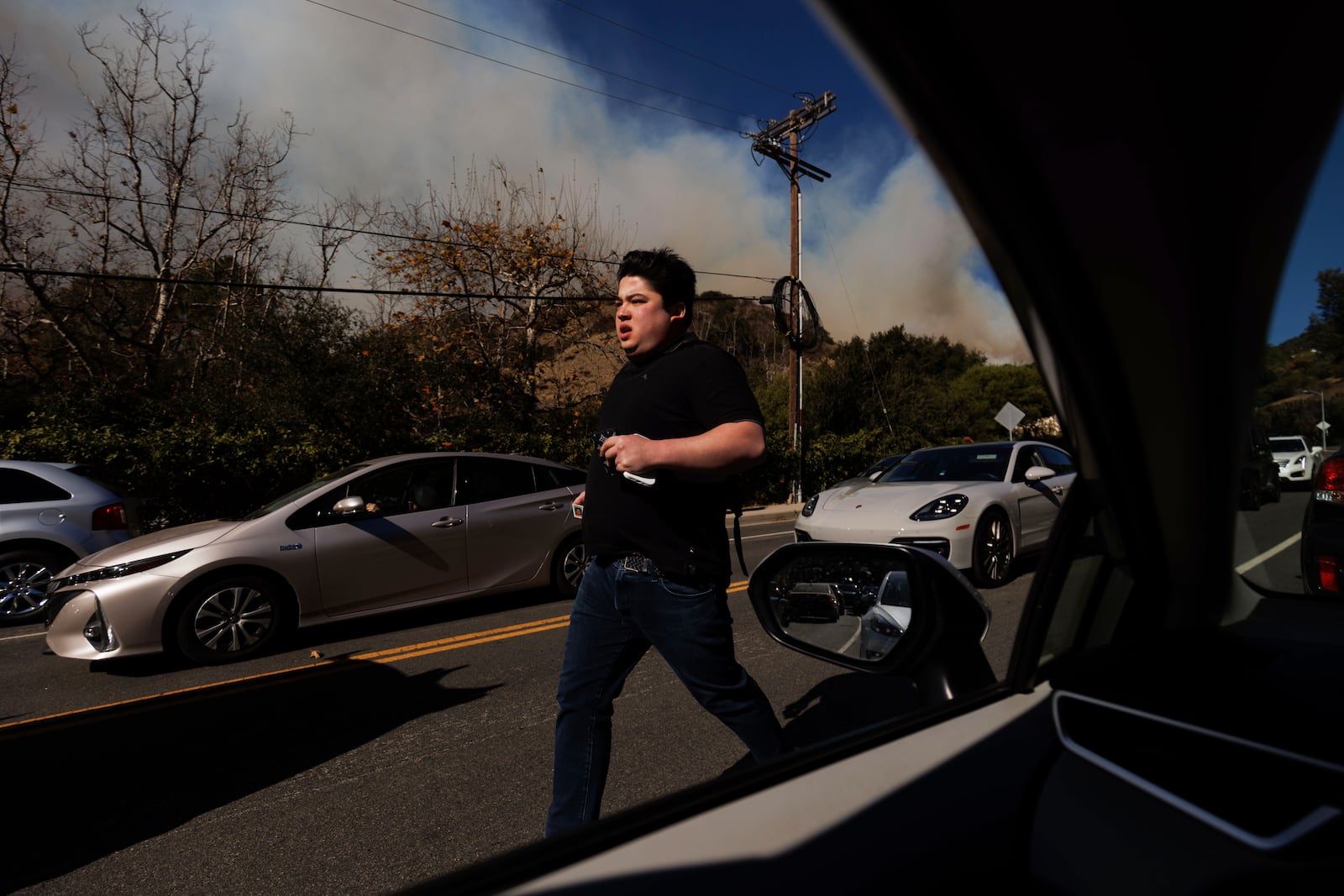 A person flees from an advancing wildfire in the Pacific Palisades neighborhood of Los Angeles Tuesday, Jan. 7, 2025. (AP Photo/Ethan Swope)