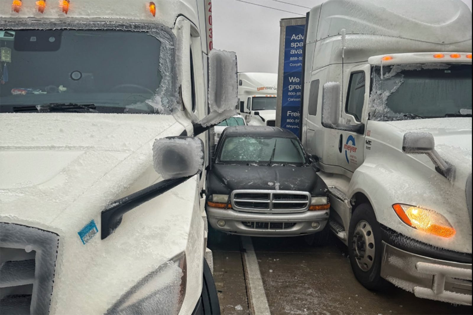 In a photo released by the McPherson County, a car is wedged between two trucks during icy weather Saturday, Jan. 4, 2024, in Salina, Kansas. (McPherson County via AP)