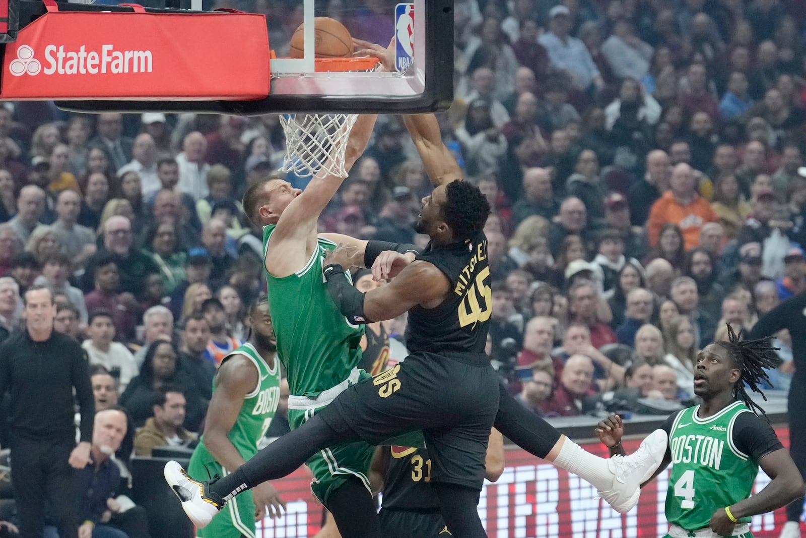 Cleveland Cavaliers guard Donovan Mitchell (45) dunks over Boston Celtics center Kristaps Porzingis, left, in the first half of an NBA basketball game, Tuesday, Feb. 4, 2025, in Cleveland. (AP Photo/Sue Ogrocki)