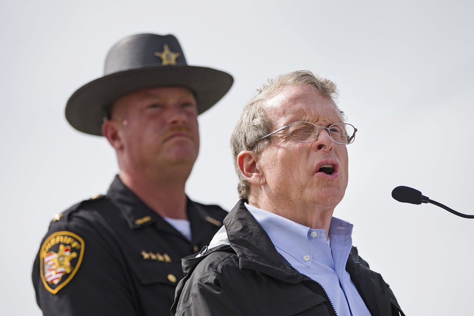 FILE - In this April 27, 2016, file photo, Ohio state Attorney General Mike DeWine, right, alongside Pike County Sheriff Charles Reader, left, speaks to reporters about the unsolved killings of seven adults and a teenage boy from the Rhoden family whose bodies were found at four homes near Piketon, Ohio, on April 22, 2016, during a news conference in Waverly, Ohio. Voters in Ohio’s 2018 elections have their pick of positions on gun rights, among a crowded field of contenders vying to succeed term-limited Republican Gov. John Kasich. (AP Photo/John Minchillo, File)