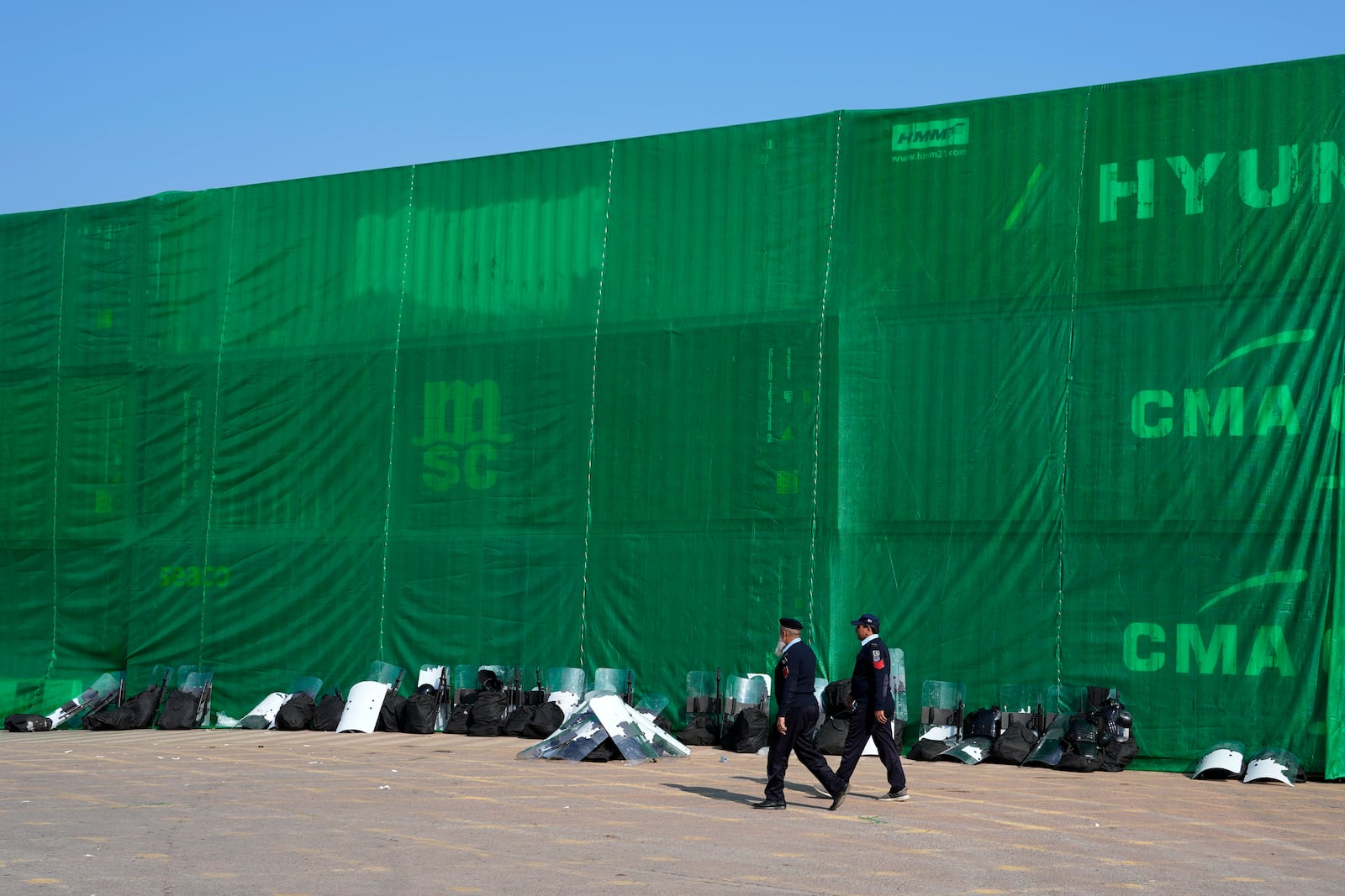 Police officers patrol at a road barricaded with shipping containers ahead of a planned rally by supporters of imprisoned former Prime Minister Imran Khan's Pakistan Tehreek-e-Insaf party, in Islamabad, Pakistan, Sunday, Nov. 24, 2024. (AP Photo/Anjum Naveed)