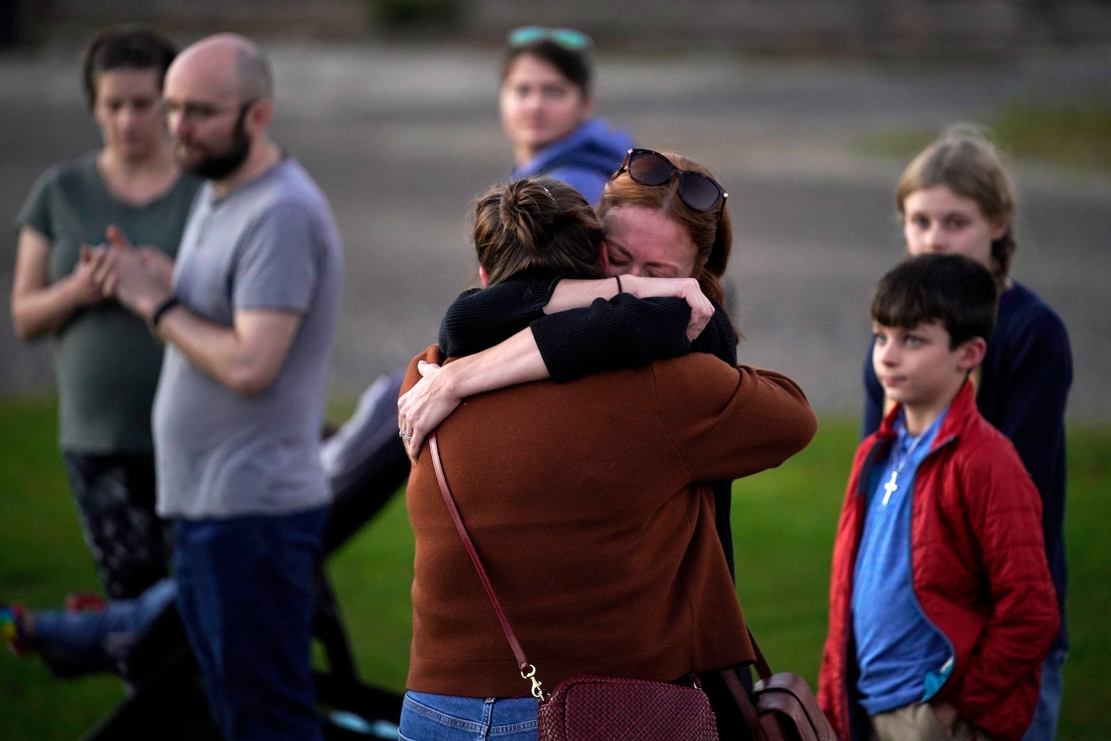 FILE - Lindsay Marlow, facing camera, hugs Courtney Majoros, in this Oct. 28, 2023 file photo, at a vigil in Lisbon Falls, Maine, for the victims of recent mass shootings. Majoros' brother, Maxx Hathaway, was one of the people killed in separate shootings in nearby Lewiston, Maine. (AP Photo/Robert F. Bukaty, File)