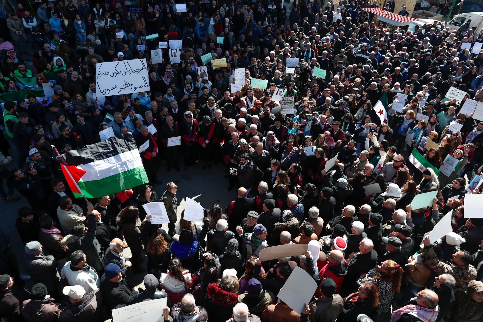 Syrian Druze hold up a placard in Arabic reads "Sweida will not be your poisoned dagger in Syria's back." as stage a demonstration against Israeli incursions into Syrian territory in the southern province of Sweida, Syria, Tuesday, Feb. 25, 2025. (AP Photo/Omar Sanadiki)