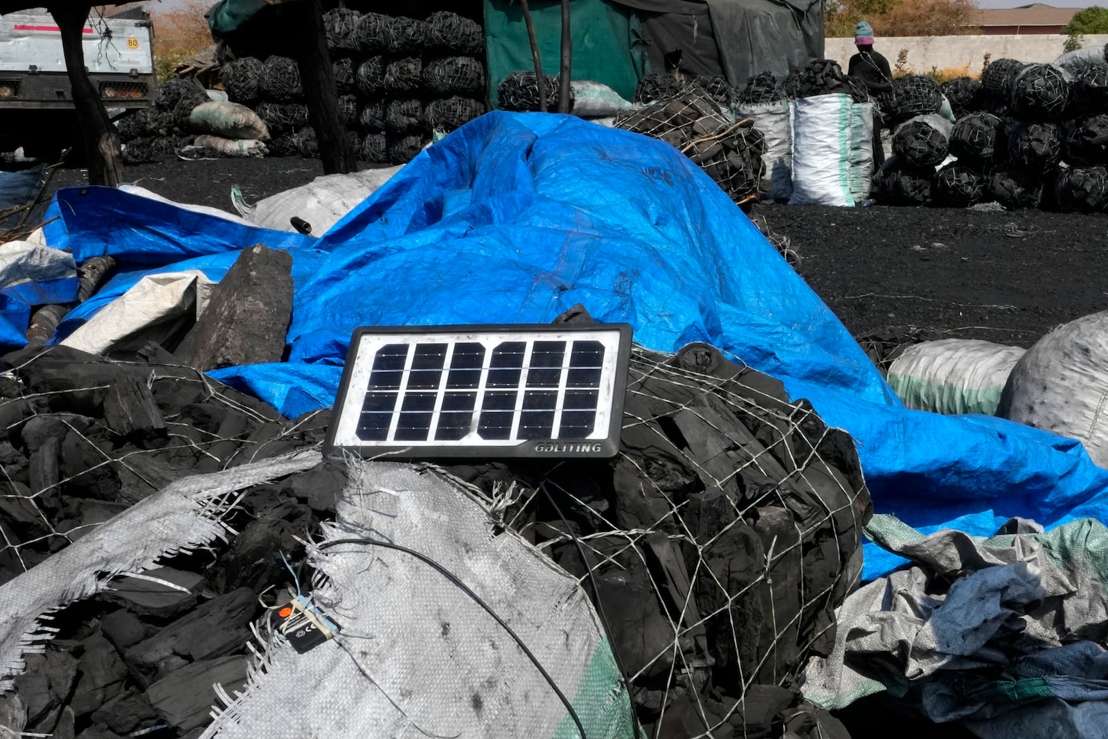 A solar panel charges a phone on bags of charcoal at Bauleni market in Lusaka, Zambia, Tuesday, Sept. 17, 2024. (AP Photo/Themba Hadebe)