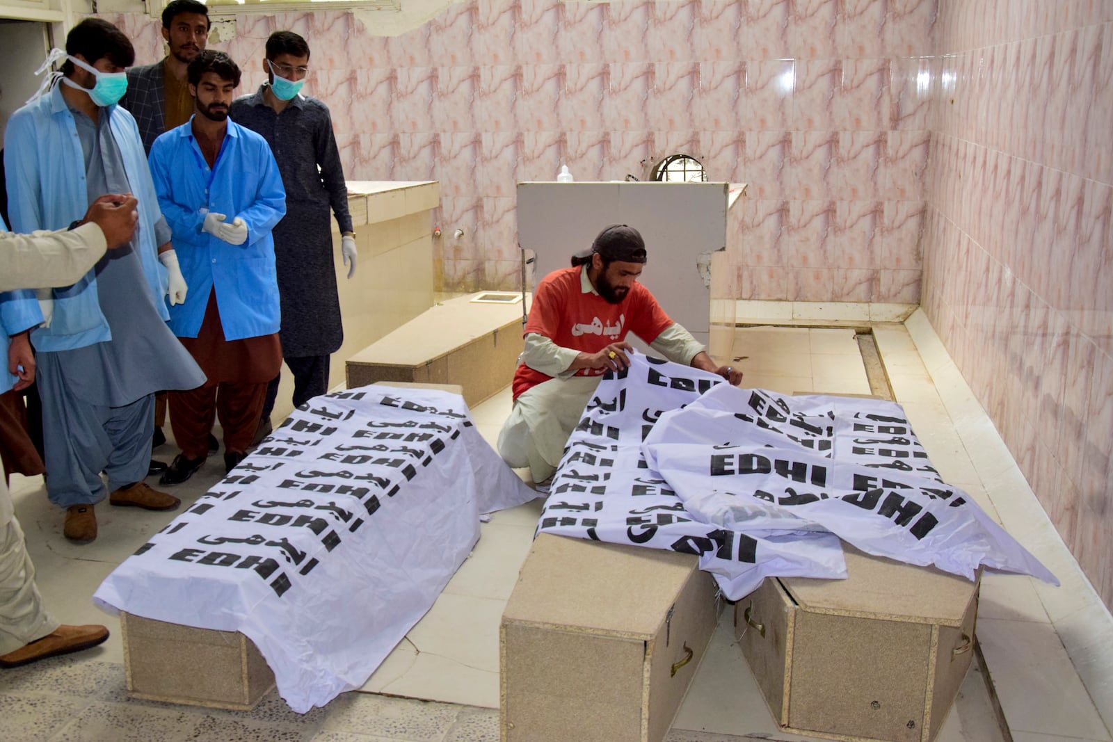 Rescue workers gather around coffins containing the bodies of victims following a train attack upon arrival at a hospital in Quetta, Pakistan's southwestern Balochistan province, Thursday March 13, 2025. (AP Photo/Arshad Butt)