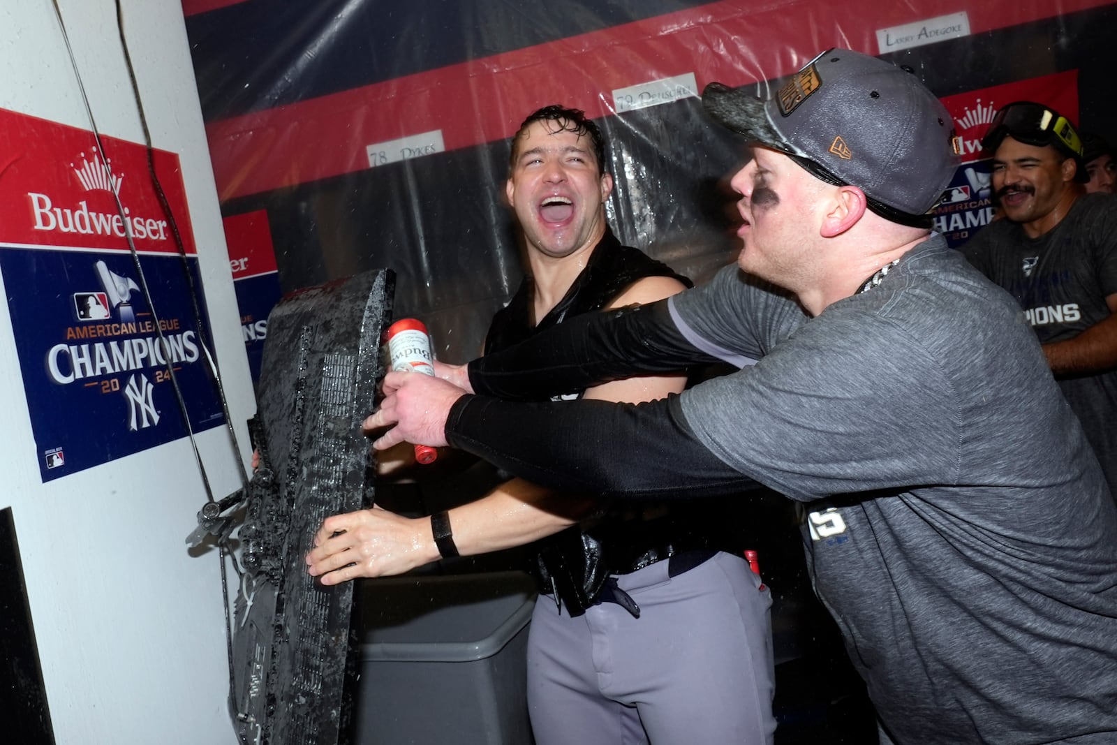 New York Yankees' Tommy Kahnle, left, and Alex Verdugo celebrate in clubhouse after Game 5 of the baseball AL Championship Series against the Cleveland Guardians Sunday, Oct. 20, 2024, in Cleveland. The Yankees won 5-2 to advance to the World Series. (AP Photo/Godofredo A. Vásquez )