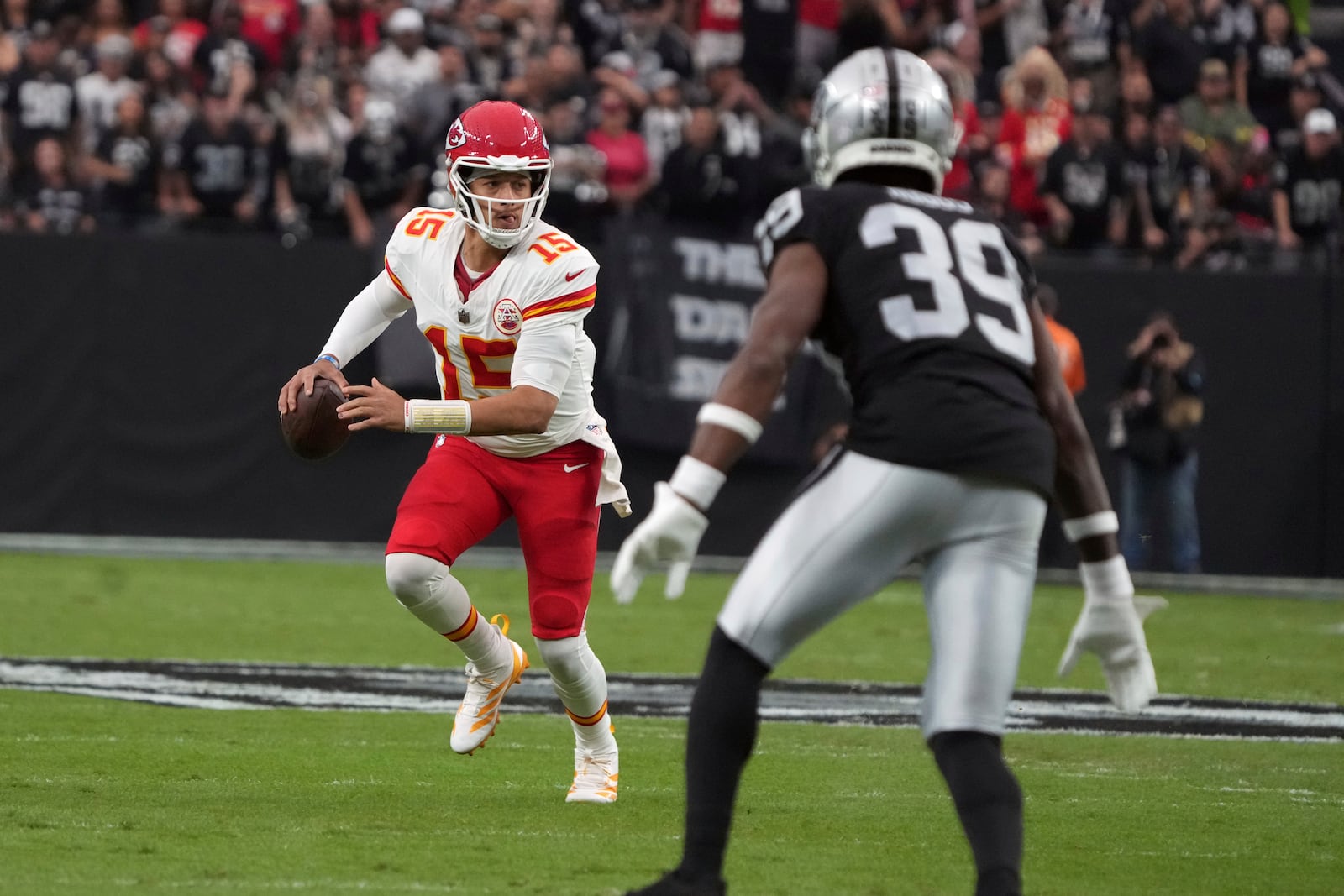 Kansas City Chiefs quarterback Patrick Mahomes (15) scrambles as Las Vegas Raiders cornerback Nate Hobbs (39) defends during the first half of an NFL football game Sunday, Oct. 27, 2024, in Las Vegas. (AP Photo/Rick Scuteri)