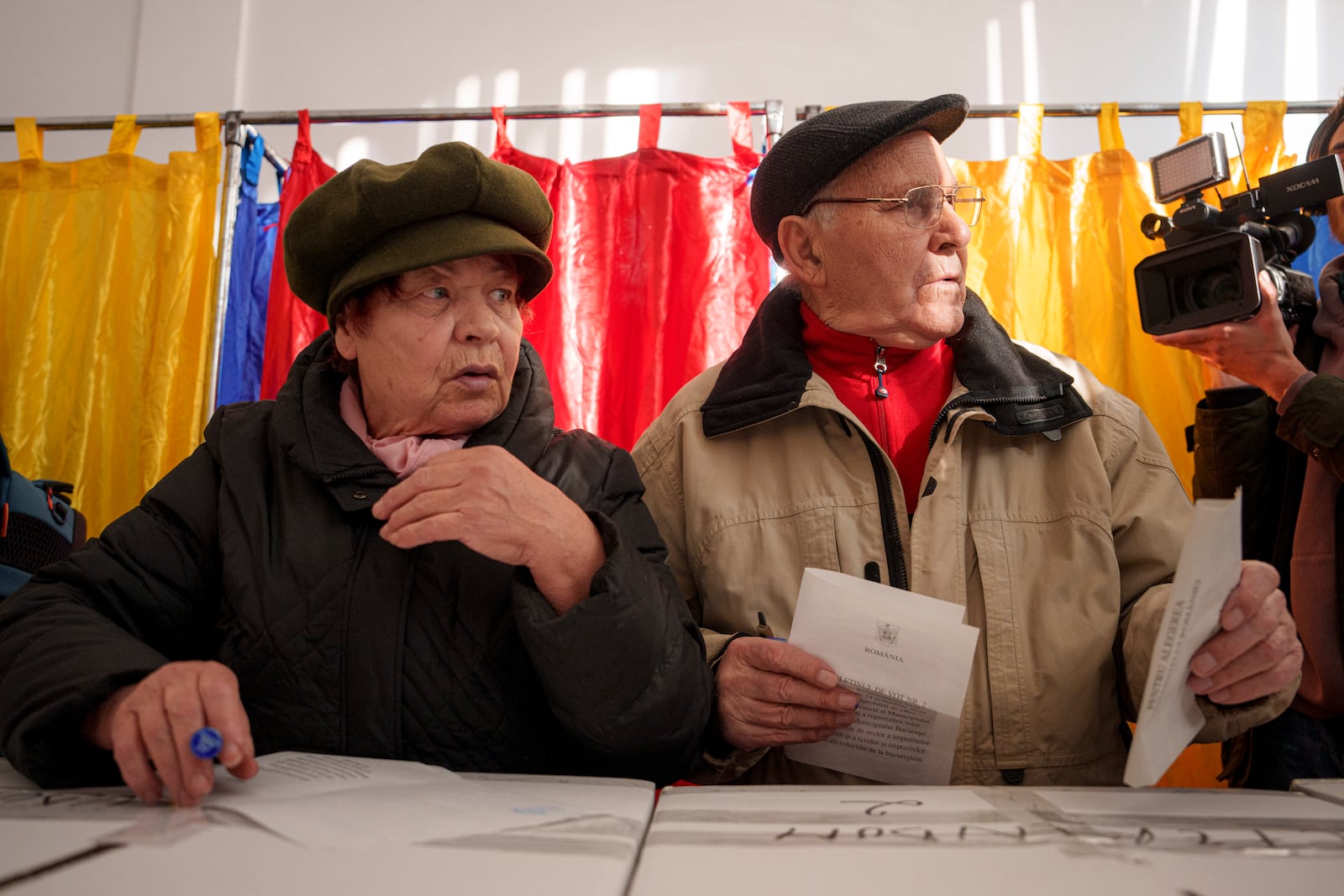 Two persons prepare to cast their vote in the country's presidential elections, in Bucharest, Romania, Sunday, Nov. 24, 2024. (AP Photo/Andreea Alexandru)