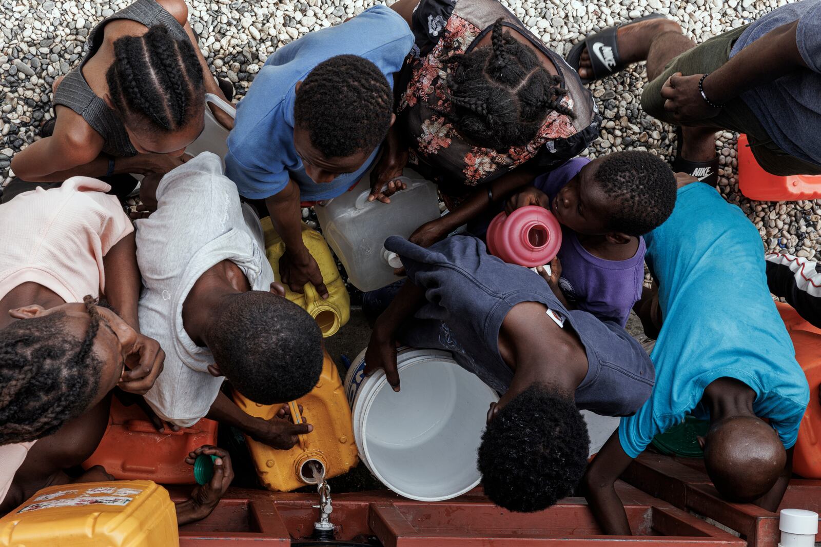 
                        People crowd around a spigot with containers for water at Lycée Marie Jeanne, a school that has become a camp for Haitians escaping violence, in Port-au-Prince, Haiti, Sept. 22, 2024. Some school buildings are in gang-occupied territory or have become de facto shelters for people forced from their homes, leaving hundreds of thousands of Haiti’s children with no chance for formal learning. (Adriana Zehbrauskas/The New York Times)
                      