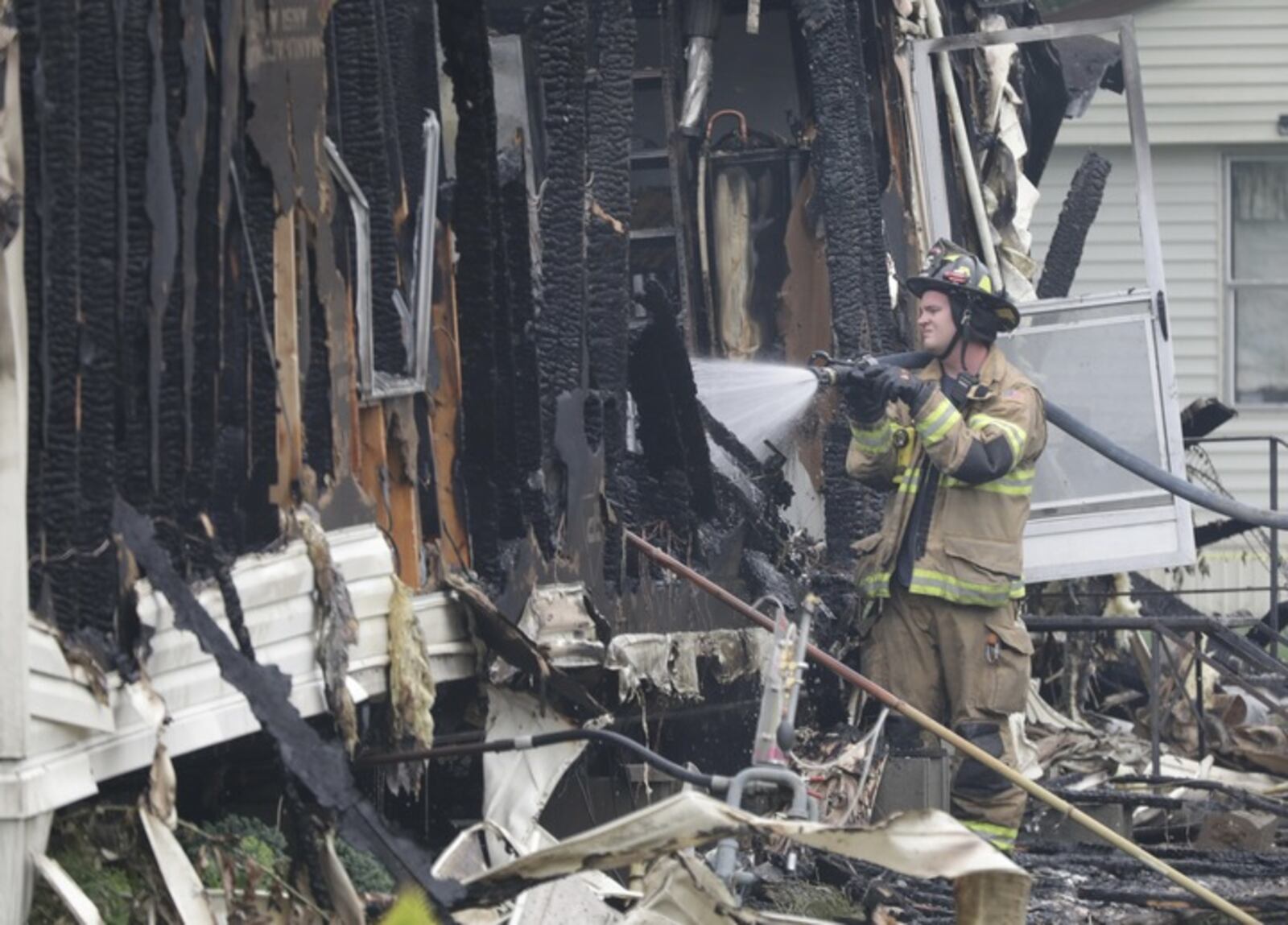 A fire finishes putting out the trailer fire in the Harmony Estates mobile home park Sunday. BILL LACKEY/STAFF