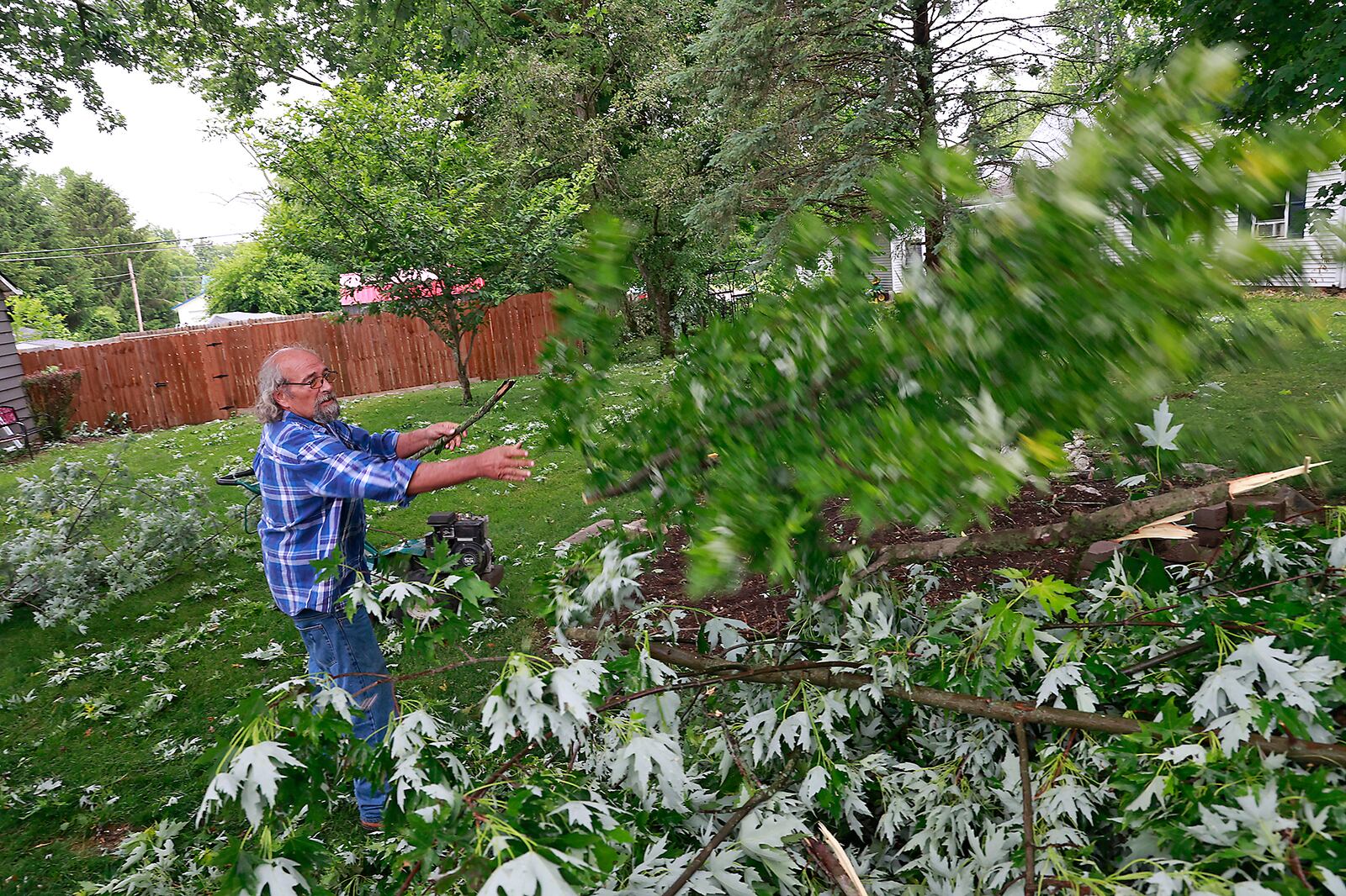 Pat Schaefer, a Christiansburg resident, cleans the tree limbs out of his yard Monday, June 12, 2023. A storm Sunday evening topped trees and knocked out power to the Champaign County town. BILL LACKEY/STAFF