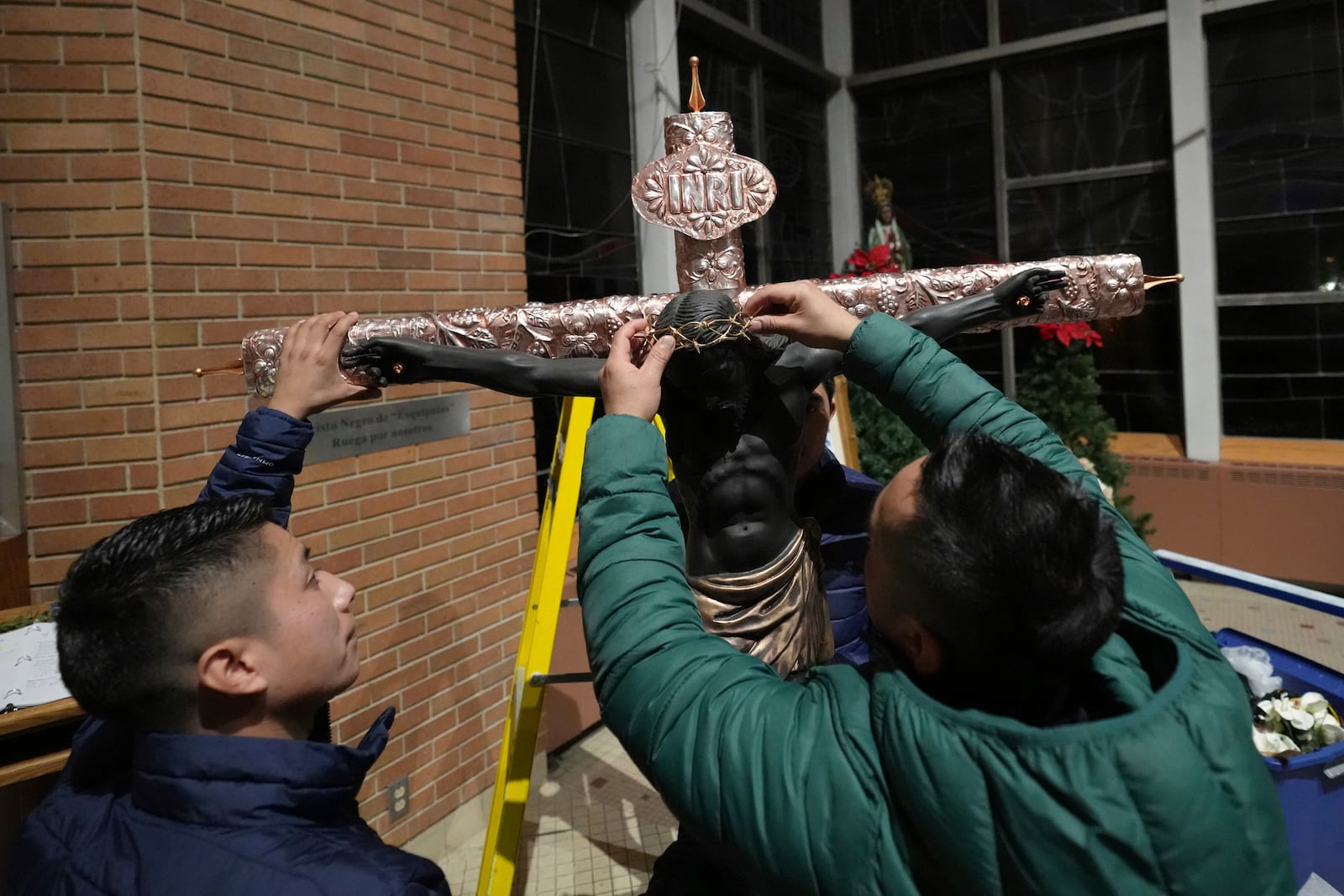 Sergio Perez puts a crown of thorns on a replica of Guatemala's Black Christ of Esquipulas statue as they prepare to celebrate its feast day at St. Mary's Catholic Church in Worthington, Minnesota, Saturday, Jan. 11, 2025. (AP Photo/Abbie Parr)